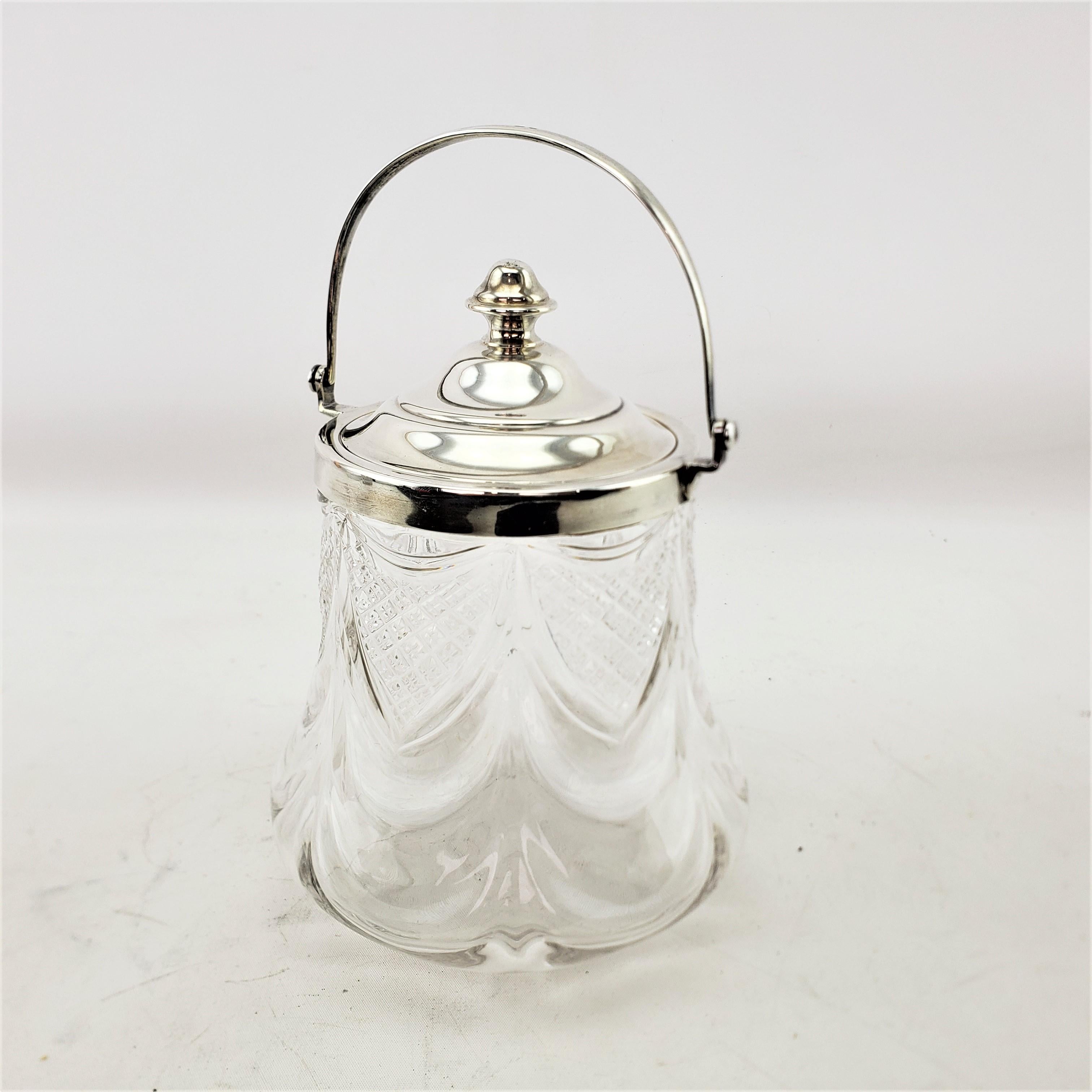 This antique biscuit barrel or covered jar was made by the well known English silversmith James Deakin & Sons in approximately 1920 and done in a period Art Deco style. This biscuit barrel is composed of clear crystal with draped diamond cut