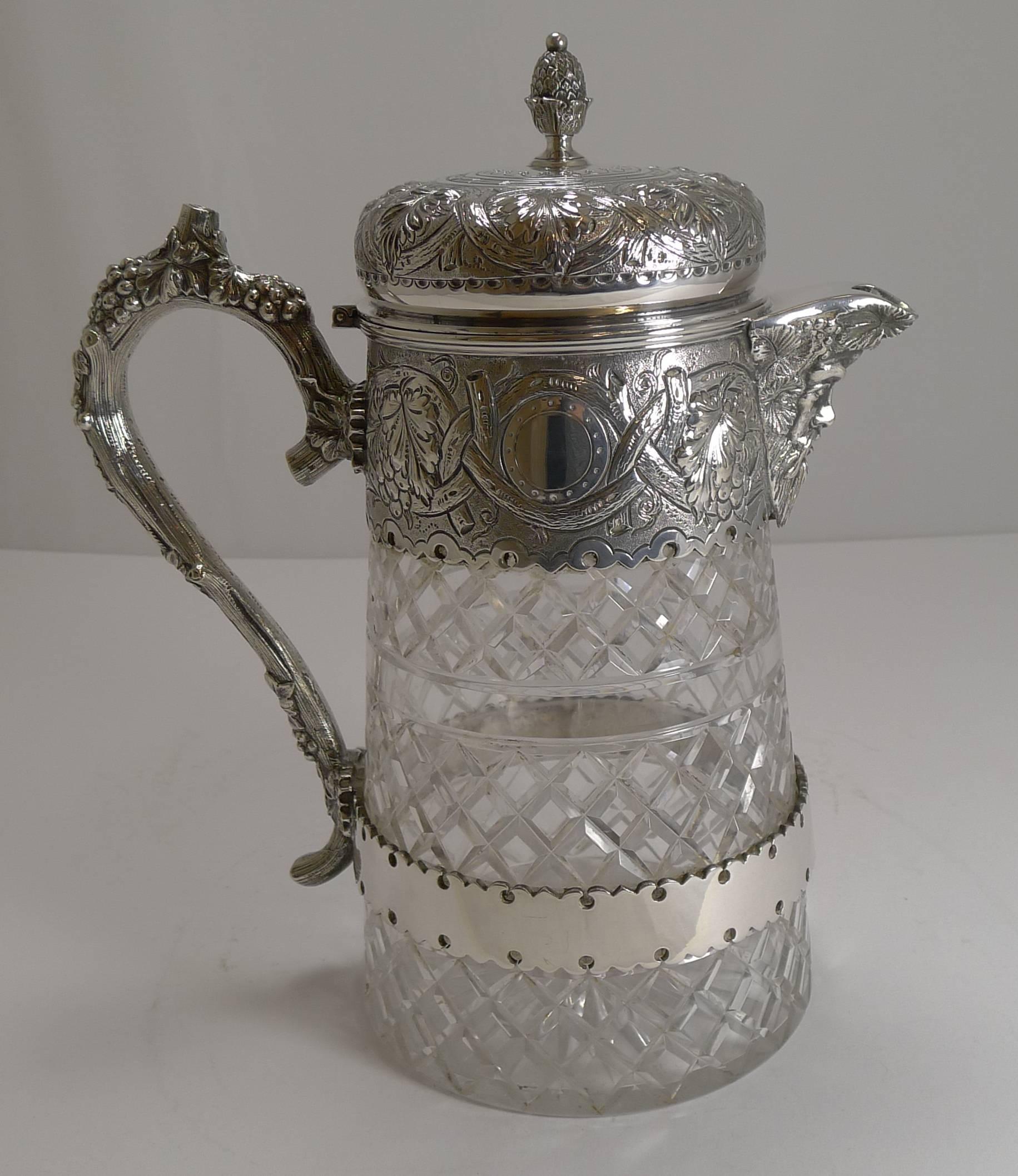 A magnificent large wine jug, wonderful quality made from a hefty piece of crystal beautifully hand-cut.

The naturalistic handle is just lovely, the collar and lid smothered with repousse or embossed Grapevine decoration. The wonderful figural