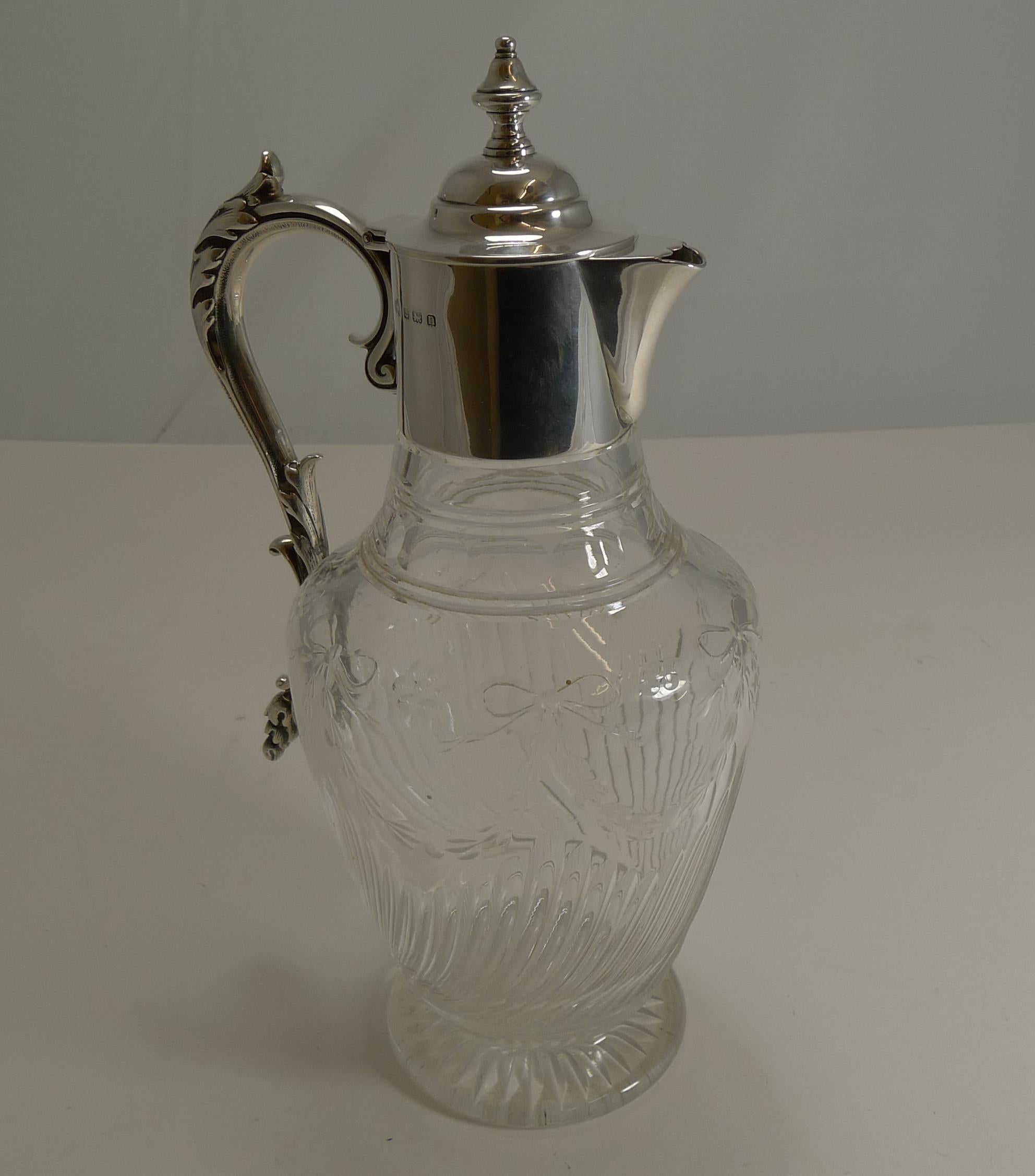 A fabulous antique crystal claret jug with the underside of the foot with a star cut. The body of the jug has long diagonal channel cuts and above this, a very pretty ribbon and bow continuous garland.

The fittings are all solid English sterling