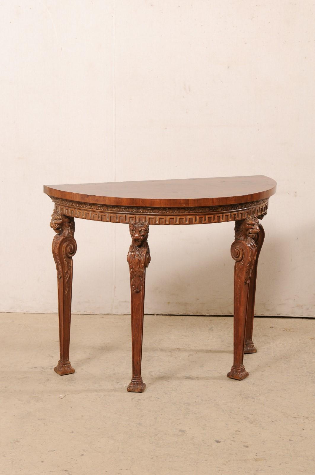 An English beautifully-carved wood demi-lune table from the 19th century. This antique console table from England features a half-moon shaped top which overhands and rests upon an apron adorn in bands of foliage-carved trim with Greek key trim