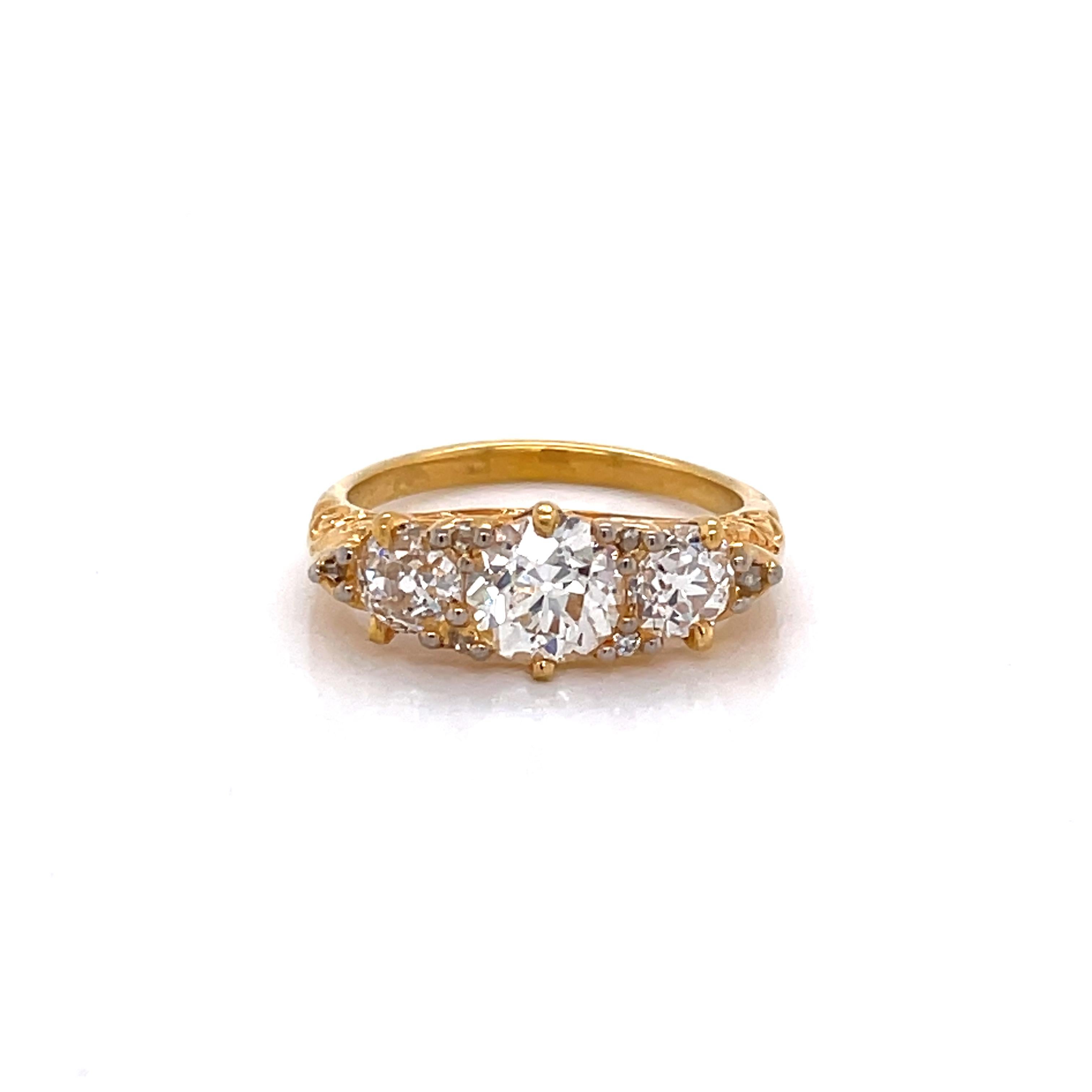 A romantic antique setting in eighteen karat 18 karat yellow gold cradles fine old European cut diamonds and illuminates this fine ring. Featured is one .90 carat G/I1 center stone which is flanked by two .345 carat H/SI diamonds and six .05 rose