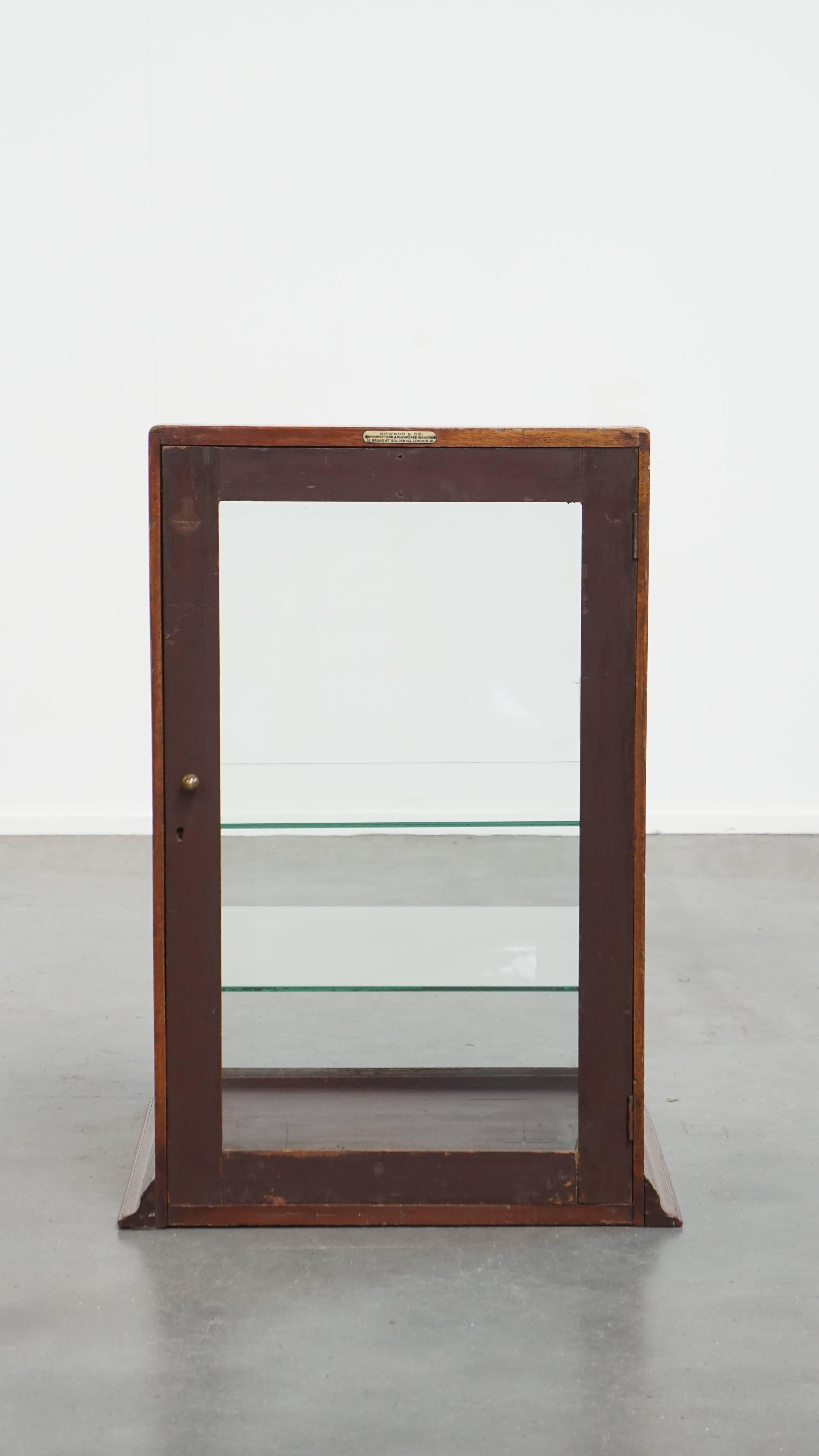 Offered: this antique decorative English display cabinet with two glass shelves and a glass door, made by Dowson & Co. This charming antique decorative cabinet is a wonderful addition to your shop, but it will also enhance your home interior.

When