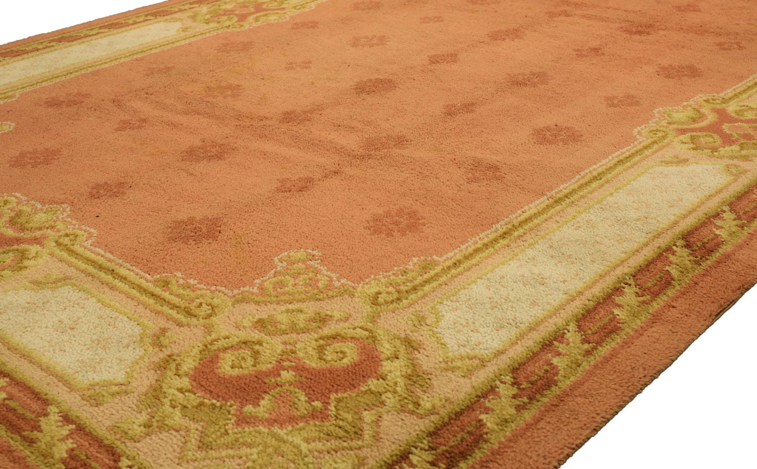 This is an antique Donegal carpet woven in Ireland during the beginning of the 20th century circa 1920's and measures 354 x 245CM in size. it has an all over field design with five columns of alternating small scale medallion motifs set on a pink