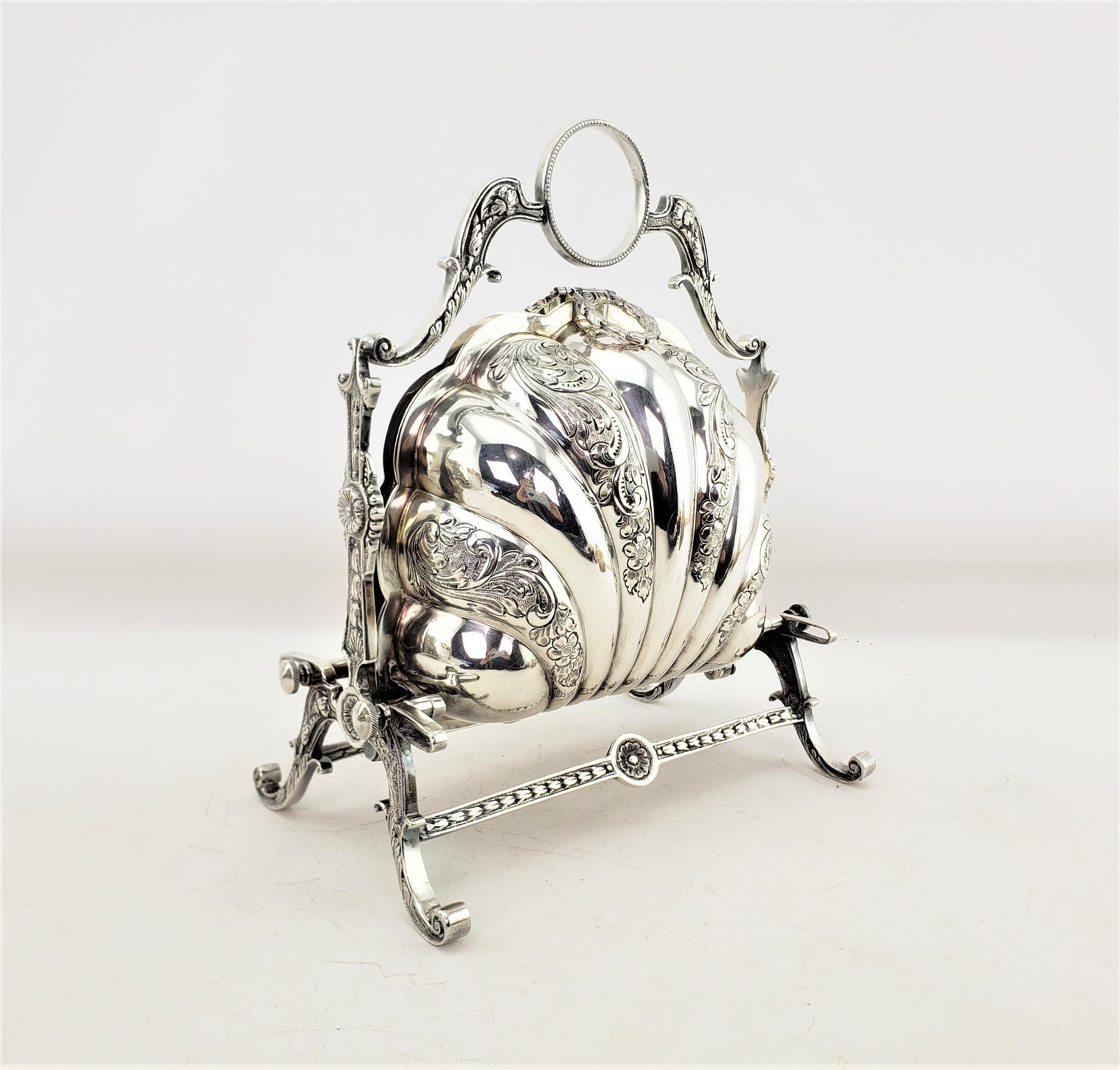 This antique biscuit barrel or box was made by the Reproduction Sheffield & Silver Plate firm of England and dates to approximately 1920 and done in a Victorian style. The server is composed of silver plate with a double shell folding sides with