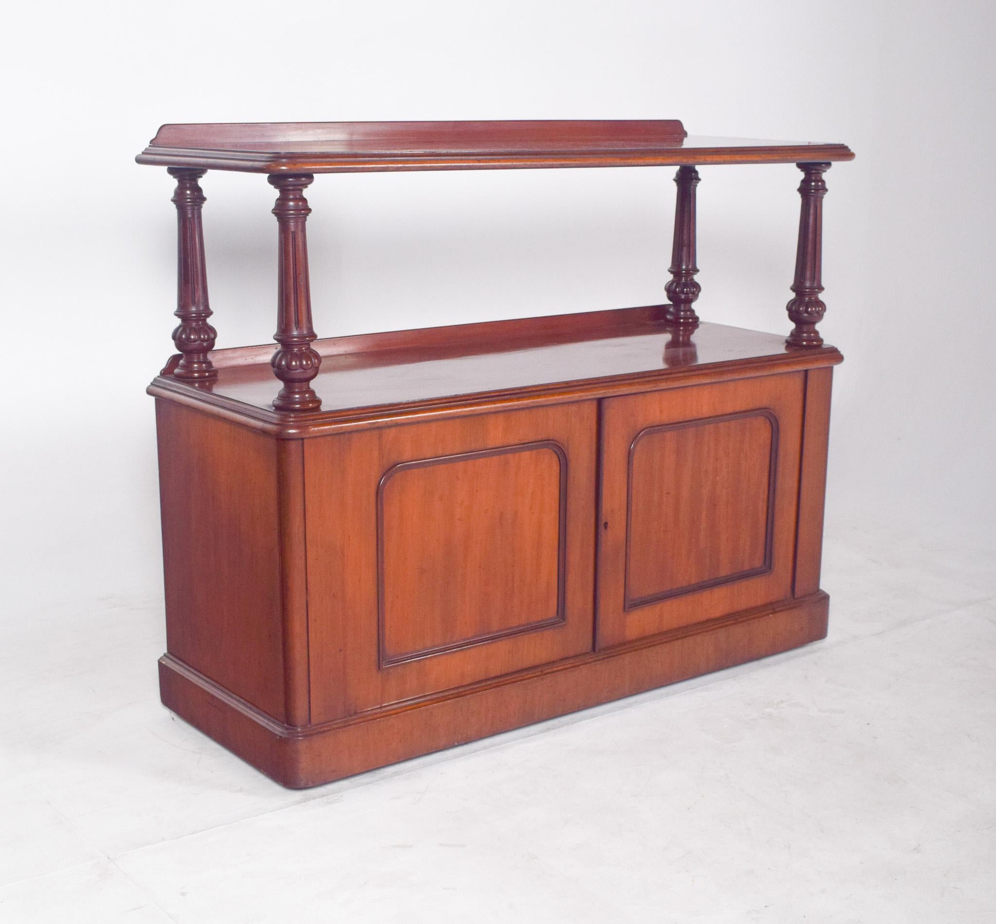 English dumbwaiter with turned columns. With two shelves, an upper one with slightly raised edges and a wider middle one, supported by elegant turned columns with baluster details. The base, with double doors with rounded corners and inlaid