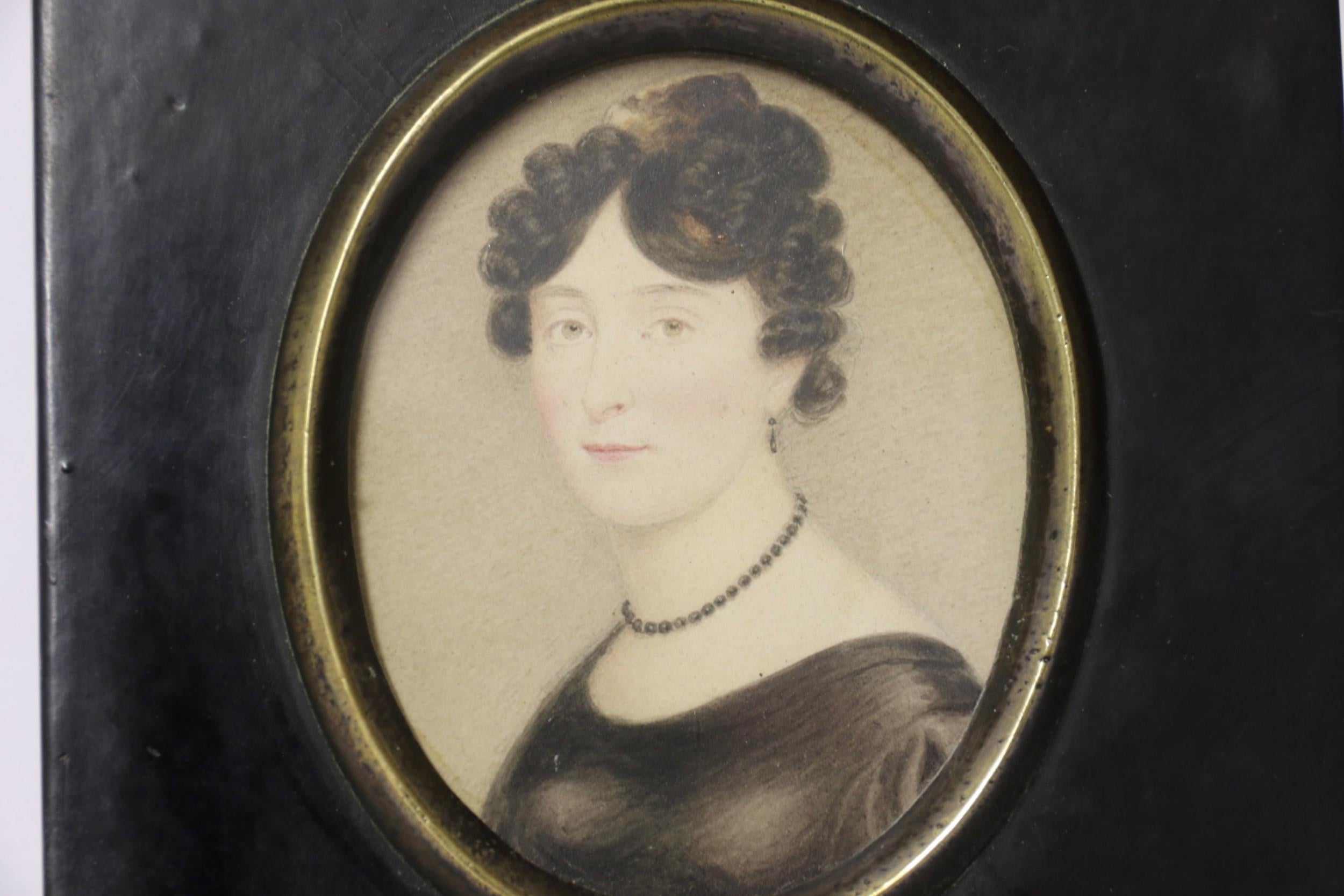 This is a early 19th century, Regency period miniature painting is in its original black lacquered frame with a bronze bezel and ivy leaf hanging ring.
Inscribed on the reverse 
