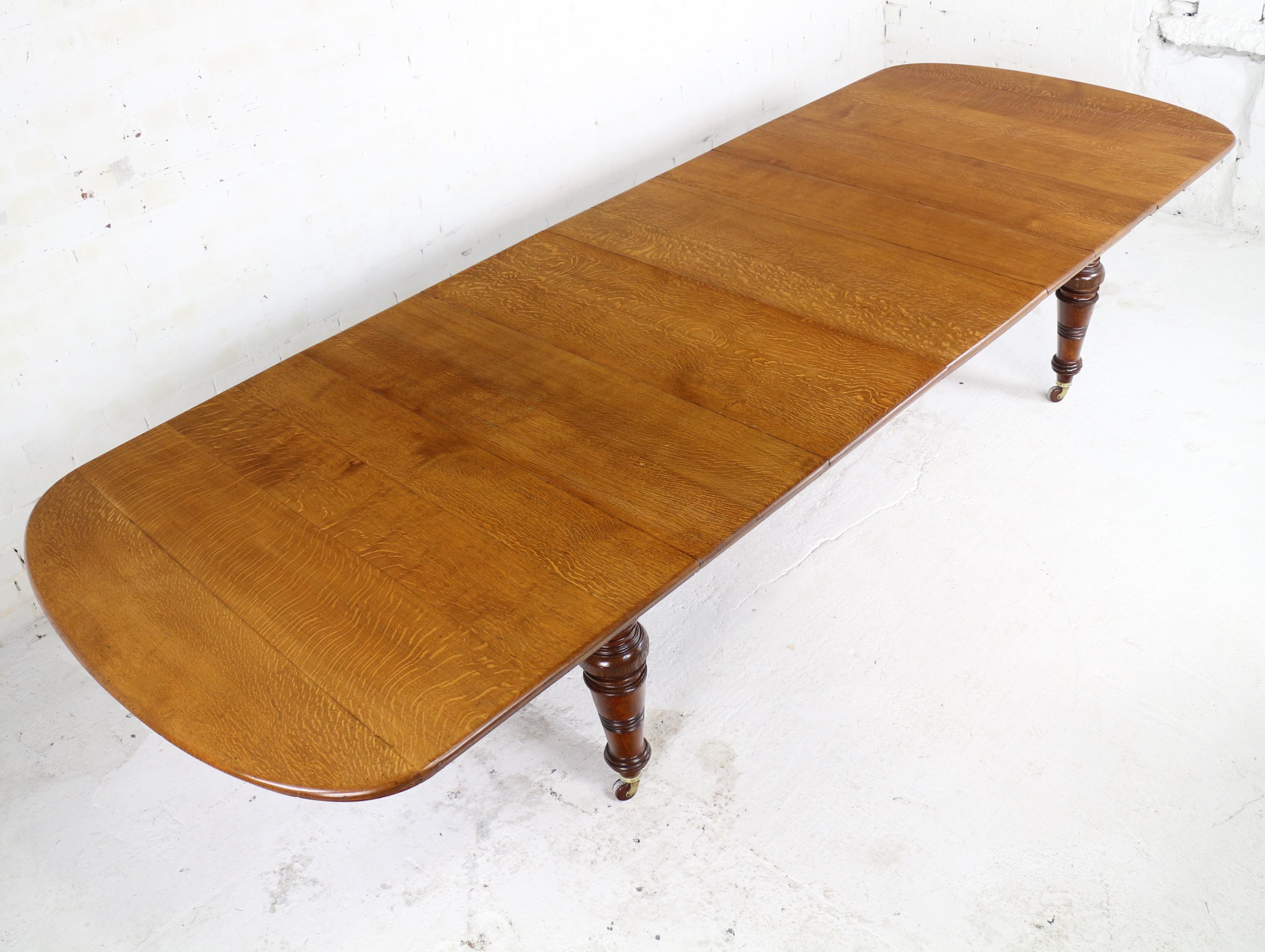 A substantially made early Victorian wind-out extending dining table in golden quarter-sawn oak with five leaves. With a rounded rectangular top finished with a moulded edge and frieze, this large table smoothly extends from 5ft 7¼in to 12ft using a