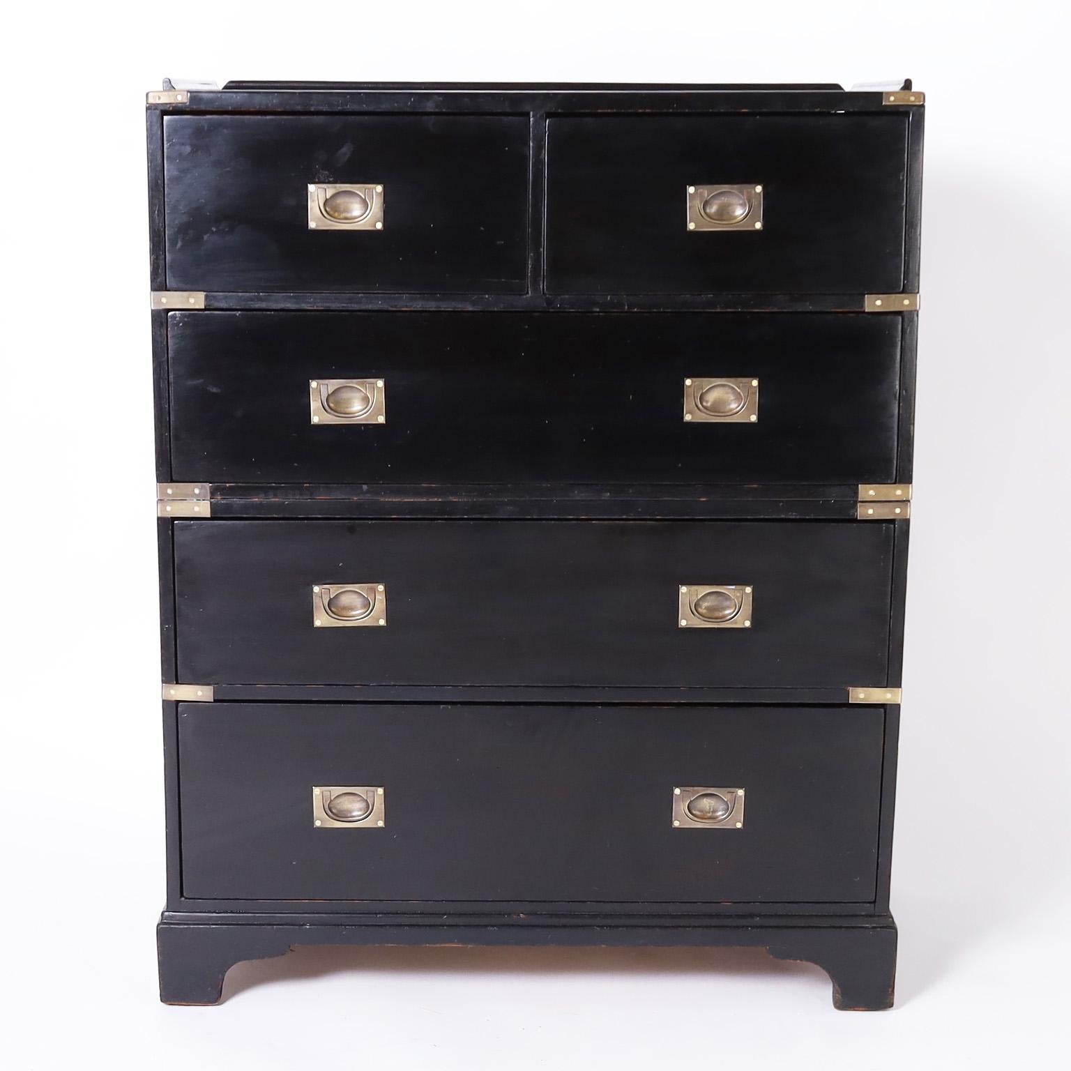 Standout British Colonial campaign chest crafted in hardwoods with five drawers having an ebonized finish, gallery on the top, brass hardware, two piece construction and classic bracket feet.
