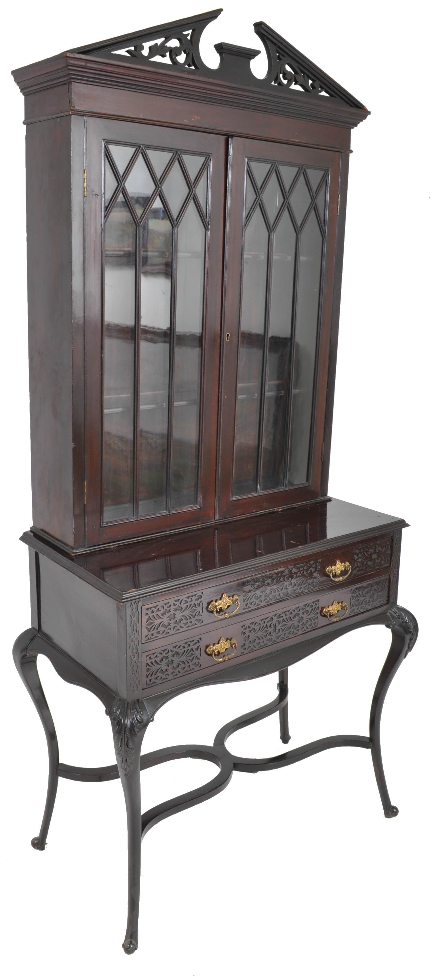 Antique English ebonized empire style cabinet / hutch / bookcase circa 1870. The cabinet is in three sections including a cornice of pierced architectural form, below a pair of doors with stylized Gothic glazing. The base having two drawers with