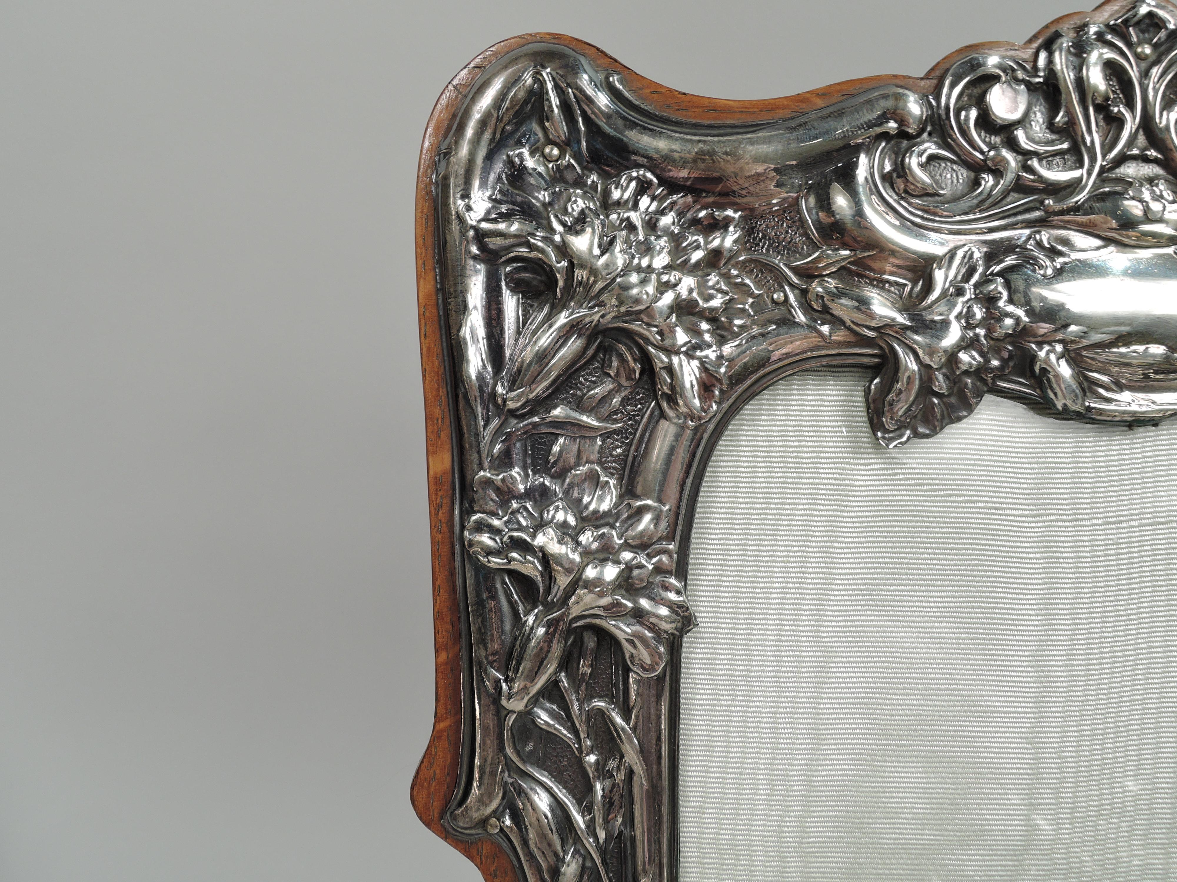 Edwardian Art Nouveau sterling silver picture frame, 1904. Shaped rectangular window in shaped surround with bracket feet. Chased ornament: Entwined tendrils and flower heads spilling over molded border and scallop shells surrounded by dynamic