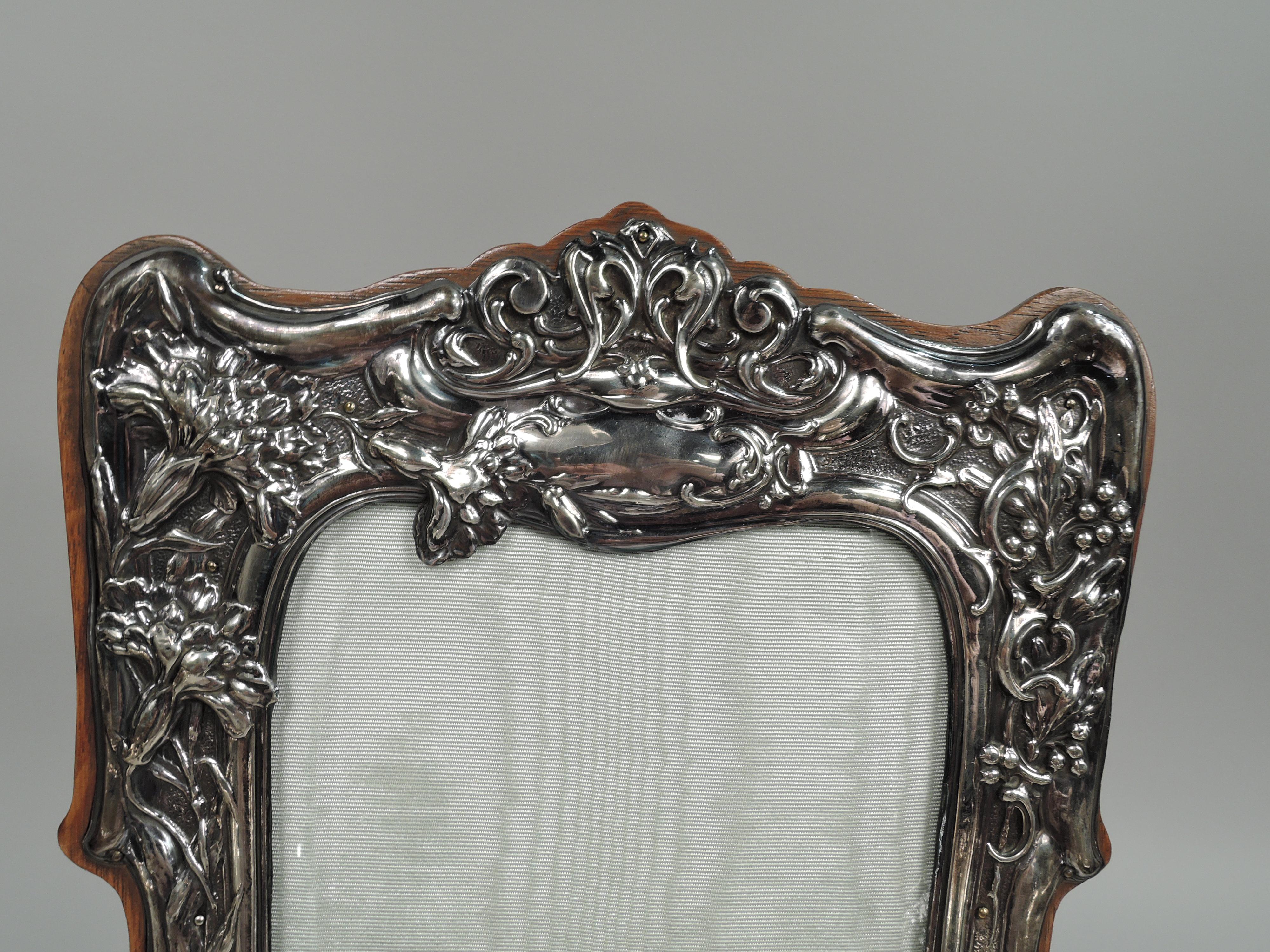 Edwardian Art Nouveau sterling silver picture frame. Made by Cornelius Saunders & Frank Shepherd in Birmingham in 1904. Shaped rectangular window in shaped surround with bracket feet. Chased ornament: Entwined tendrils and flower heads spilling over