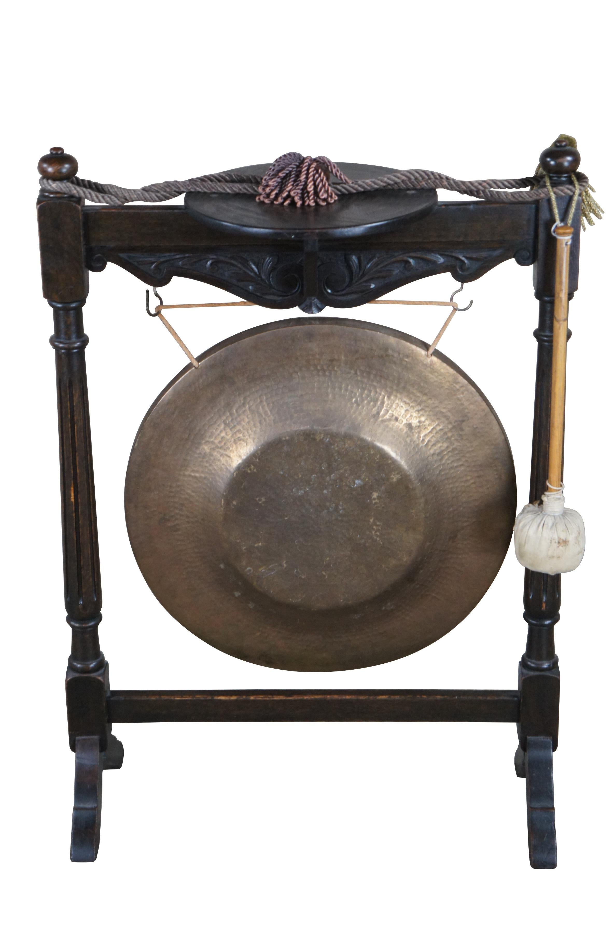 Early 1900s Edwardian floor standing dinner gong with pedestal.  Made from oak with an ornate serpentine foliate carved rail beneath rounded sculpture pedestal support.  The stand is supported by fluted columns leading to splayed legs.  Central gong