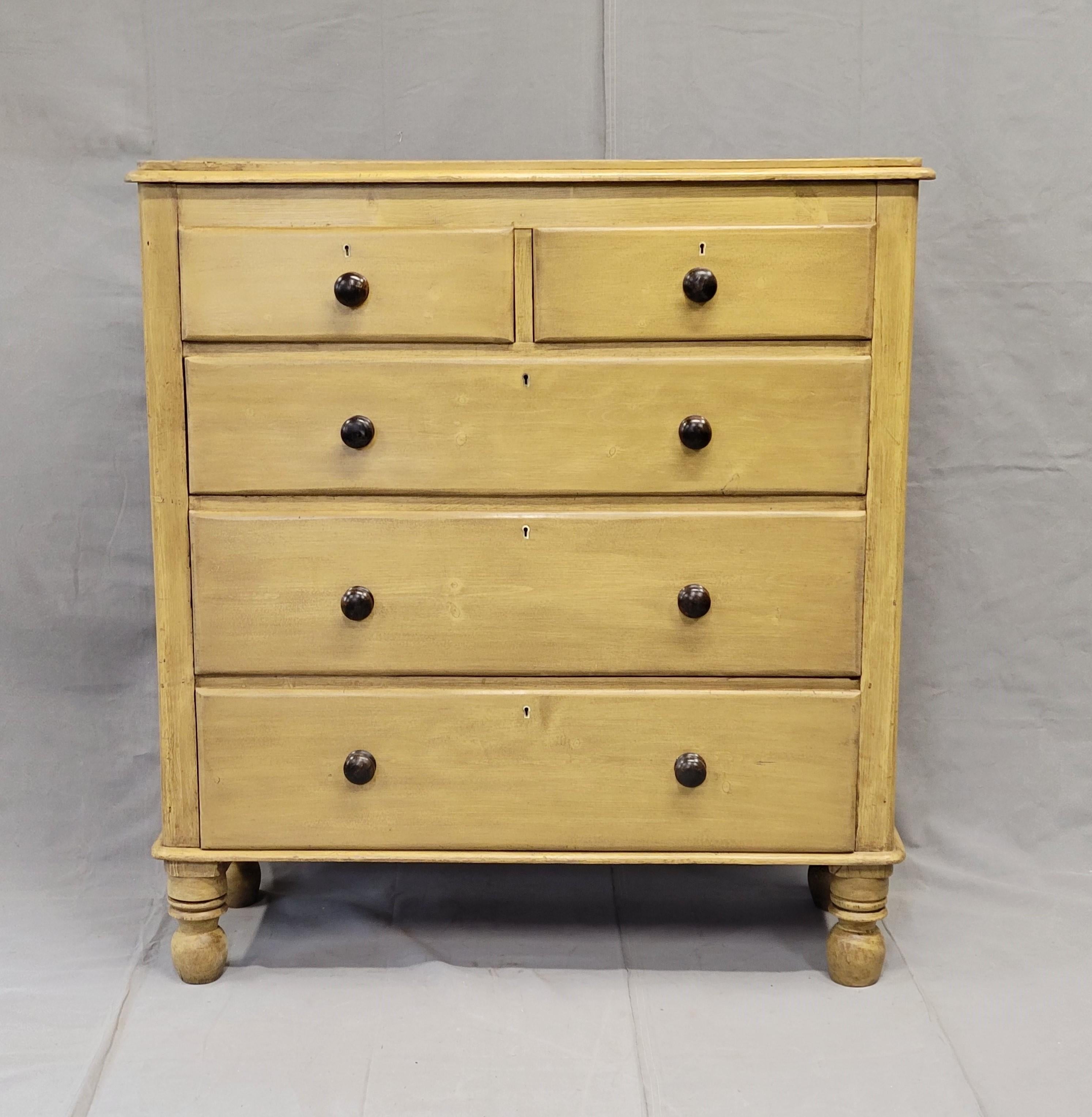 This Antique English Edwardian stately chest of drawers is made of pine and sits on oversize turned feet, adding a unique addition to your home decor. The dresser overall has the appearance of natural pine but when you look closely you realize it is