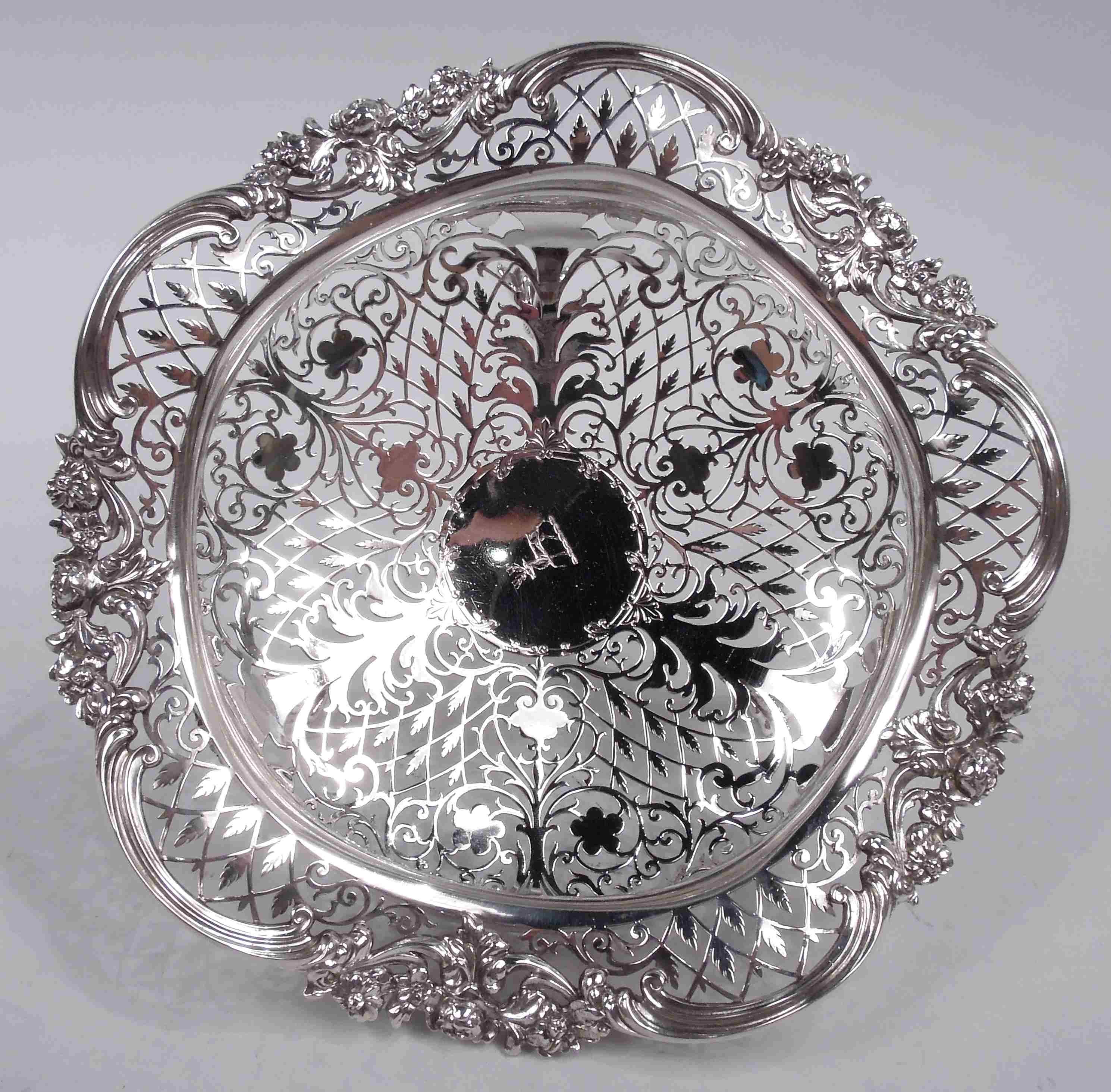 George V sterling silver bowl. Made by Goldsmiths & Silversmiths Co. Ltd in London in 1913. Bellied; rim wavy with applied scrolls and flowers. Three cast split leaf-mounted paw supports. Well has solid central round frame engraved with stag emblem,