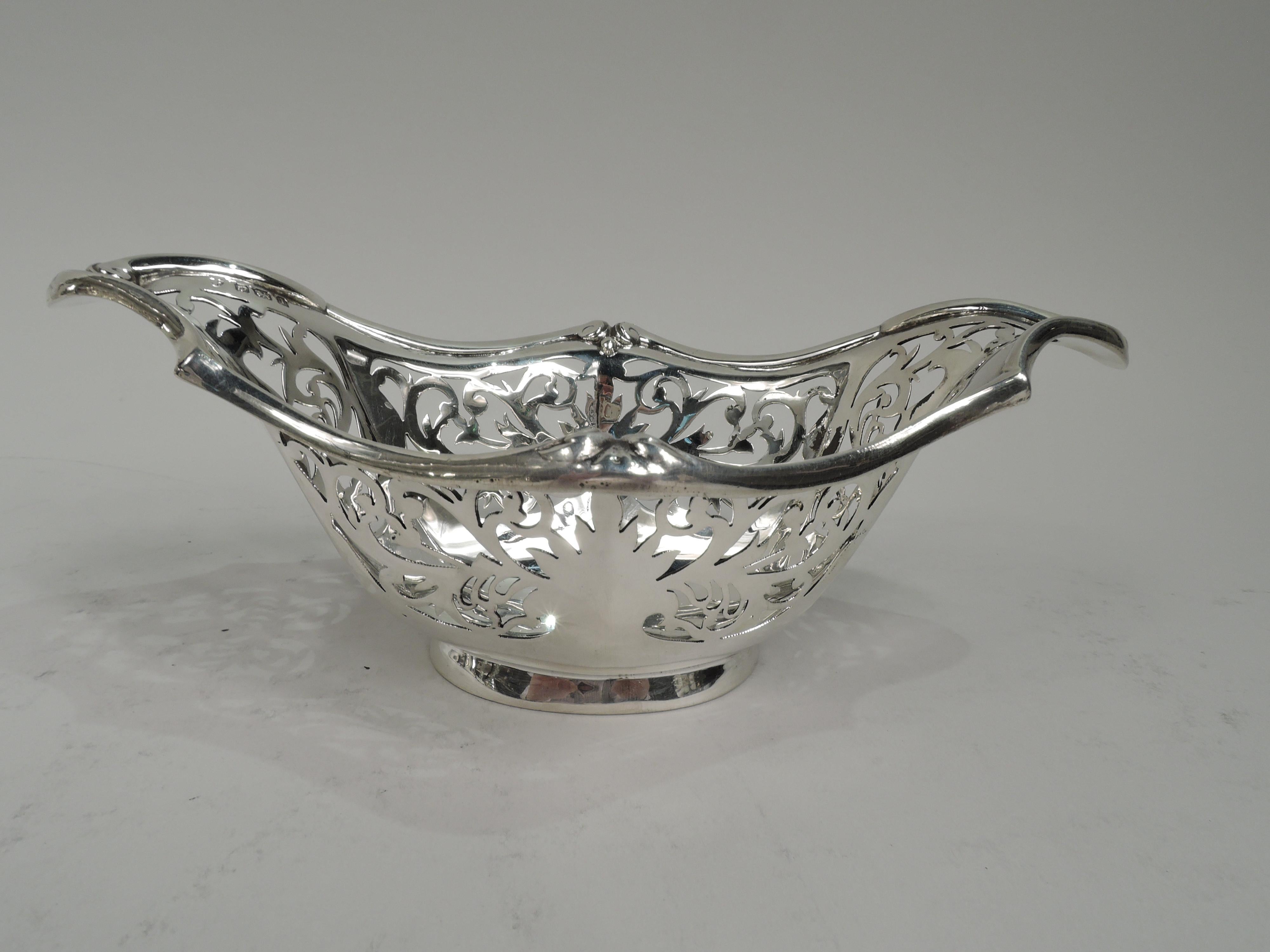 Edwardian Classical sterling silver bowl. Made by Williams, Ltd in Birmingham in 1910. Solid and faceted oval well. Sides tapering and faceted with open leafing scrollwork. Rim molded and asymmetrical with leaf-inset volute scrolls. Short and