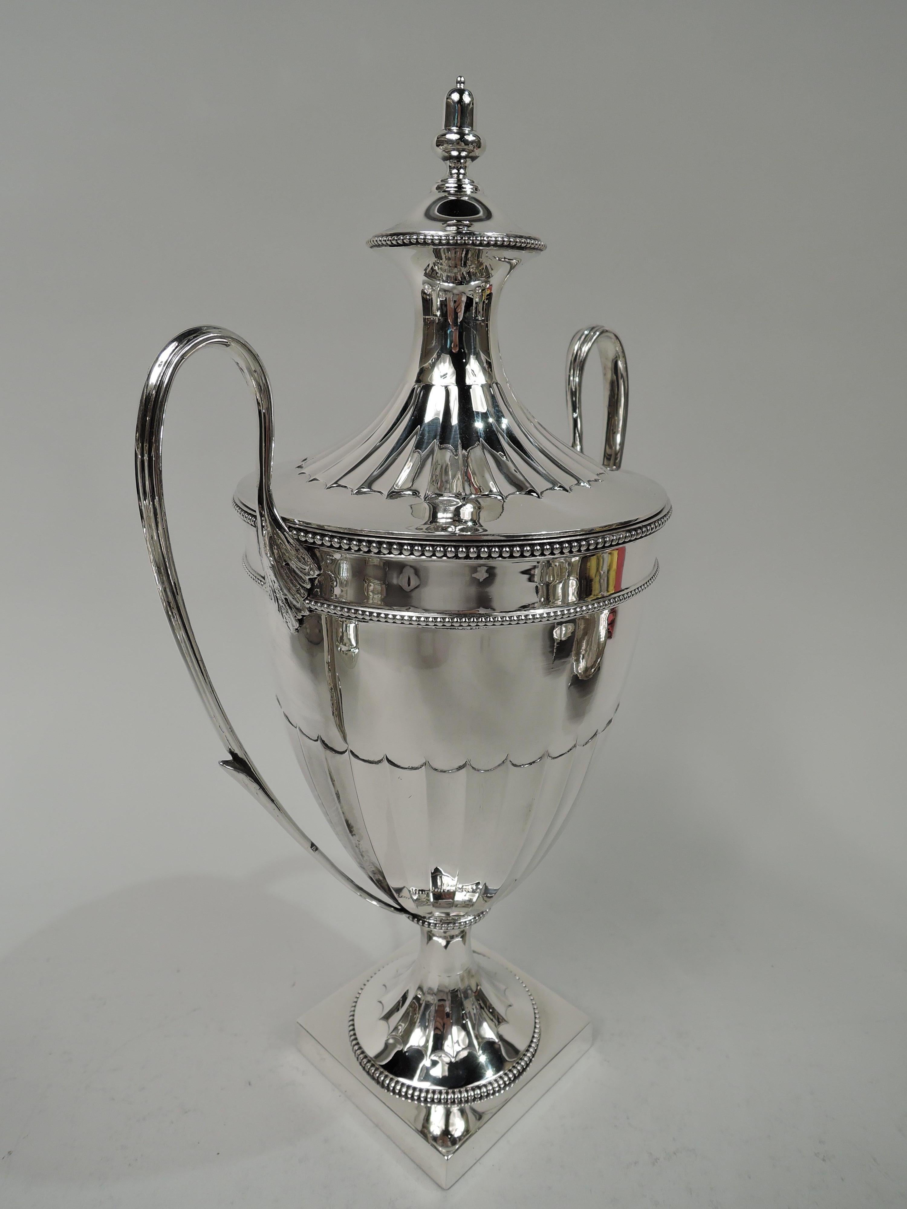 Edwardian Classical sterling silver covered urn. Made by Millar Wilkinson in London in 1905. Ovoid with reeded high-looping side handles and domed foot mounted to square base. Cover double-domed with acorn finial. Beading and fluting. Fully marked.