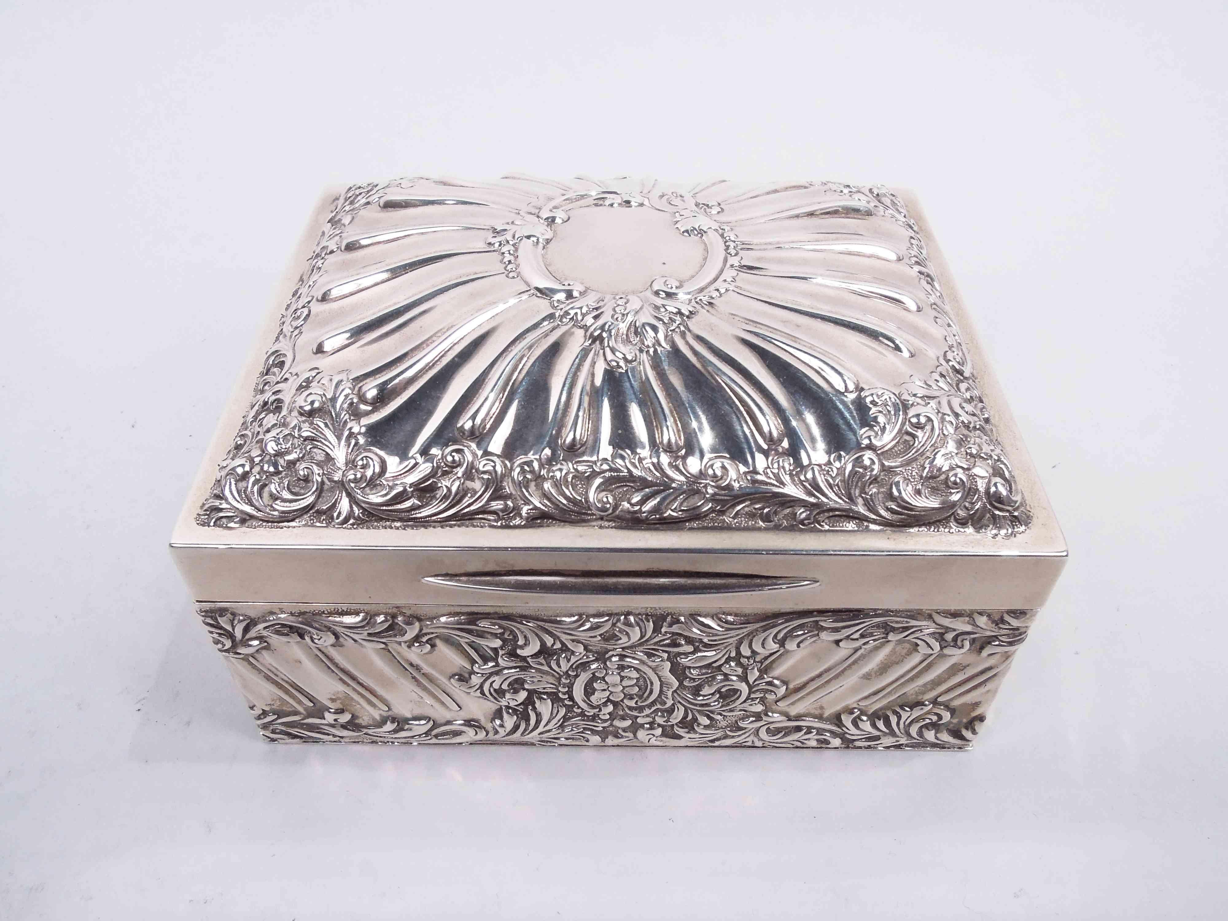 Edwardian Classical sterling silver jewelry box. Made by Goldsmiths & Silversmiths Co. Ltd in London in 1904. Rectangular; cover hinged and tabbed with curved top. Chased leaf and flower borders with twisted fluting. Cover top has central leafing