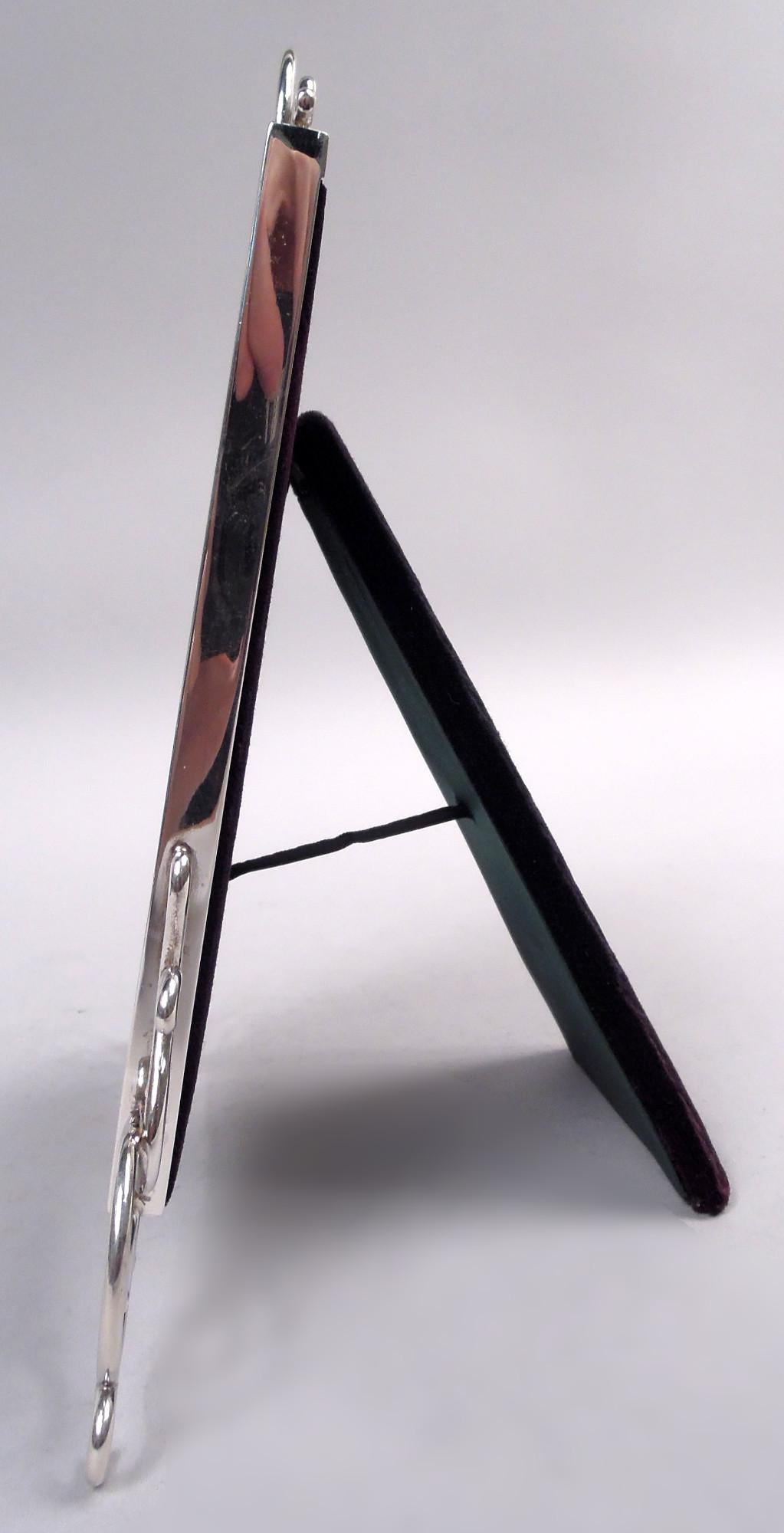 Cadre classique édouardien en argent sterling. Fabriqué par Goldsmiths & Silversmiths Co Ltd à Londres en 1901. Cadre rectangulaire uni, monté avec une volute ouverte dans la partie supérieure. Avec verre, doublure en soie, dos en velours et support