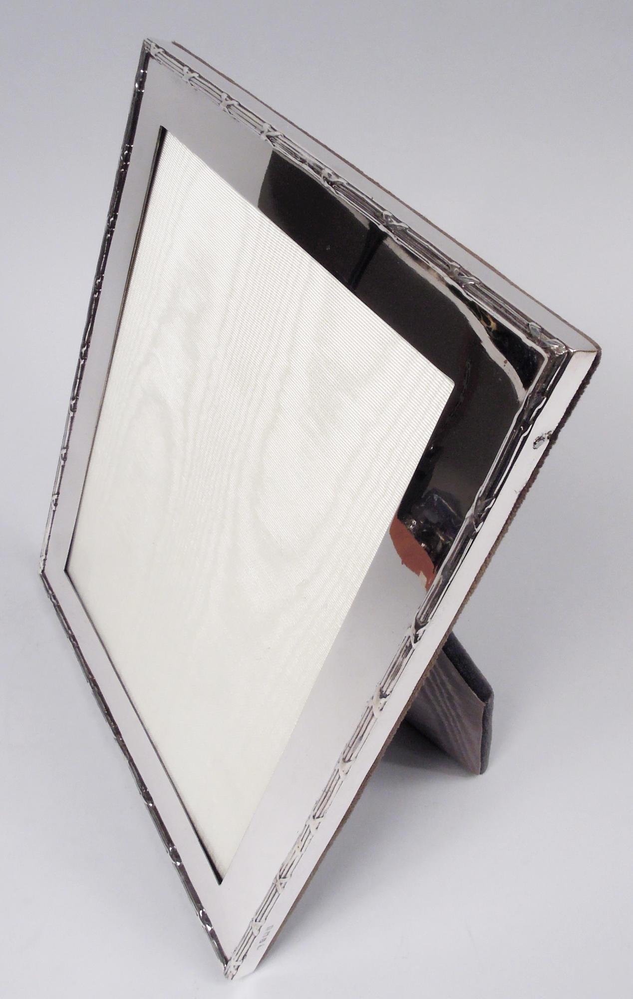 Cornice in argento sterling George V. Prodotto da A&J Zimmerman Ltd. a Birmingham nel 1915. Finestra rettangolare con cornice liscia e piatta; bordo applicato e ribattuto. Con vetro, fodera in seta, dorso in velluto e supporto a cavalletto