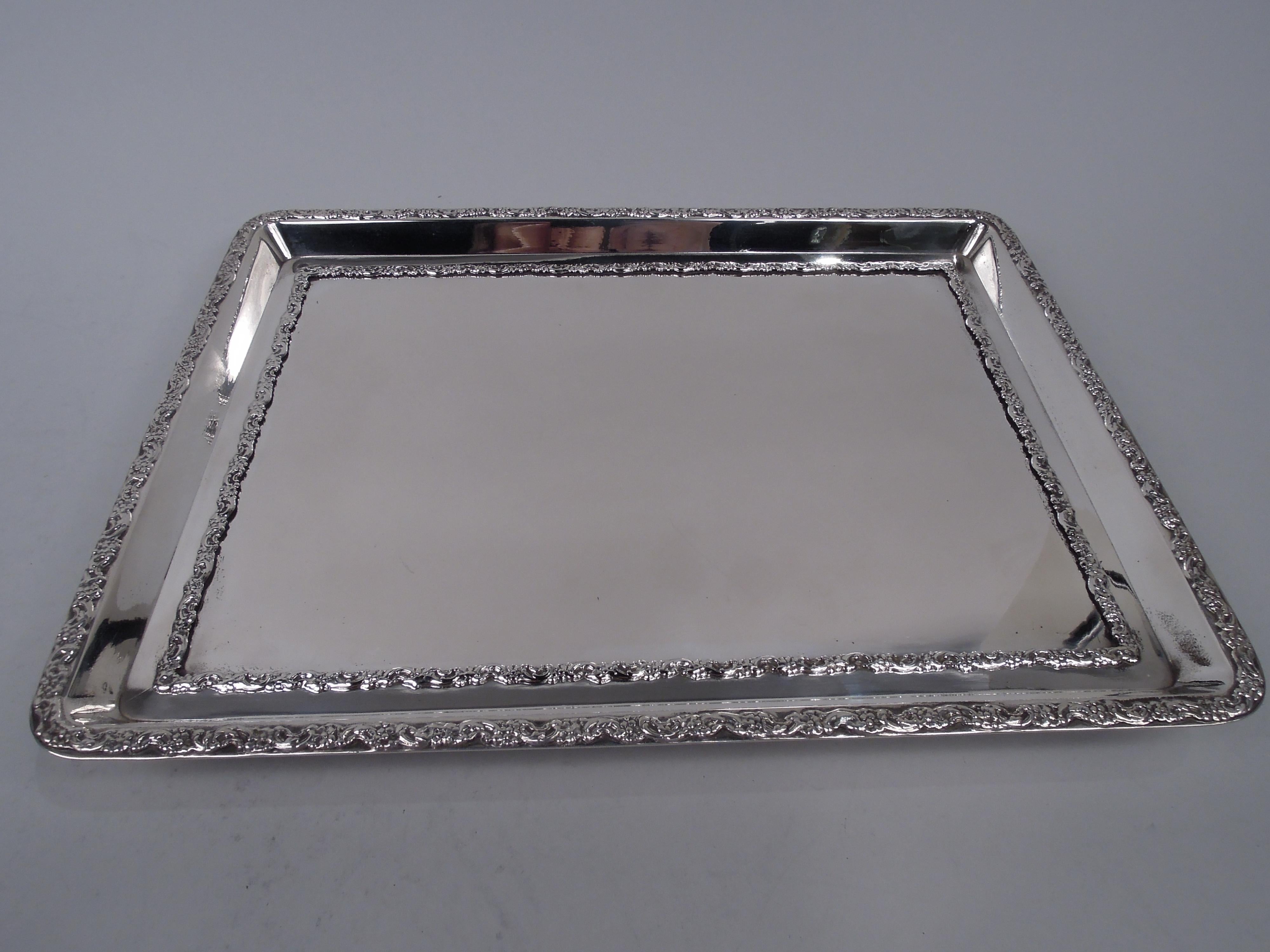 English Edwardian Classical sterling silver tray, 1908. Rectangular with tapering sides and everted rim. Scroll and flower border applied to well and rim. Corner ball supports. Fully marked including London assay stamp and stamp for New Bond Street