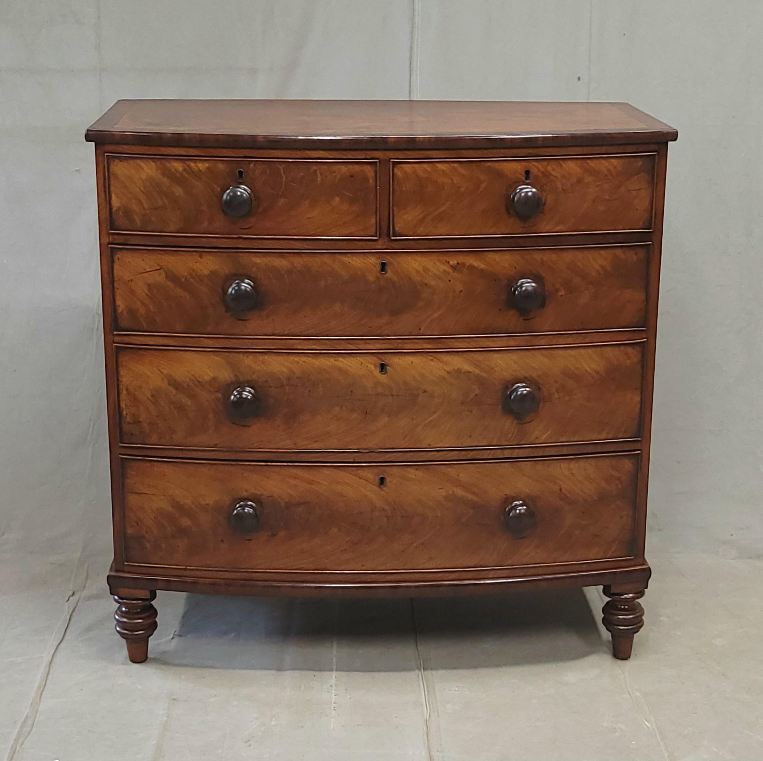 An absolutely gorgeous antique English Edwardian period (circa 1900) two-tone figured mahogany dresser chest of drawers with original knobs. This sturdy dresser has five drawers that glide smoothly and offer ample storage. The casework sits upon