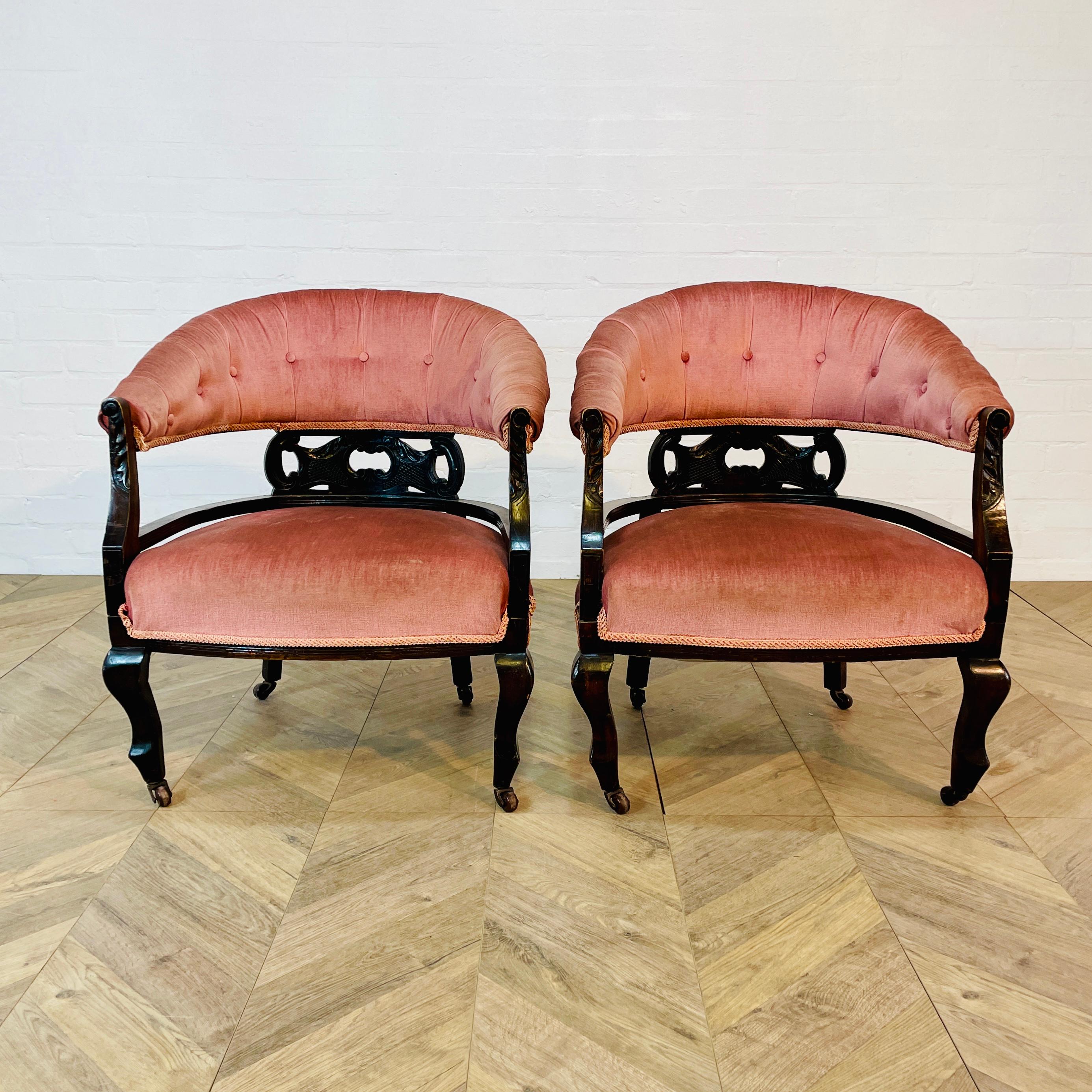A Pair of Well Proportioned, Low Armchairs, Circa 1900s.

The armchairs features a lovely curved back with detailed work and it sit on castors.

The pink upholstery is in good antique condition, with no visible scuffs or marks (as pictured).

The