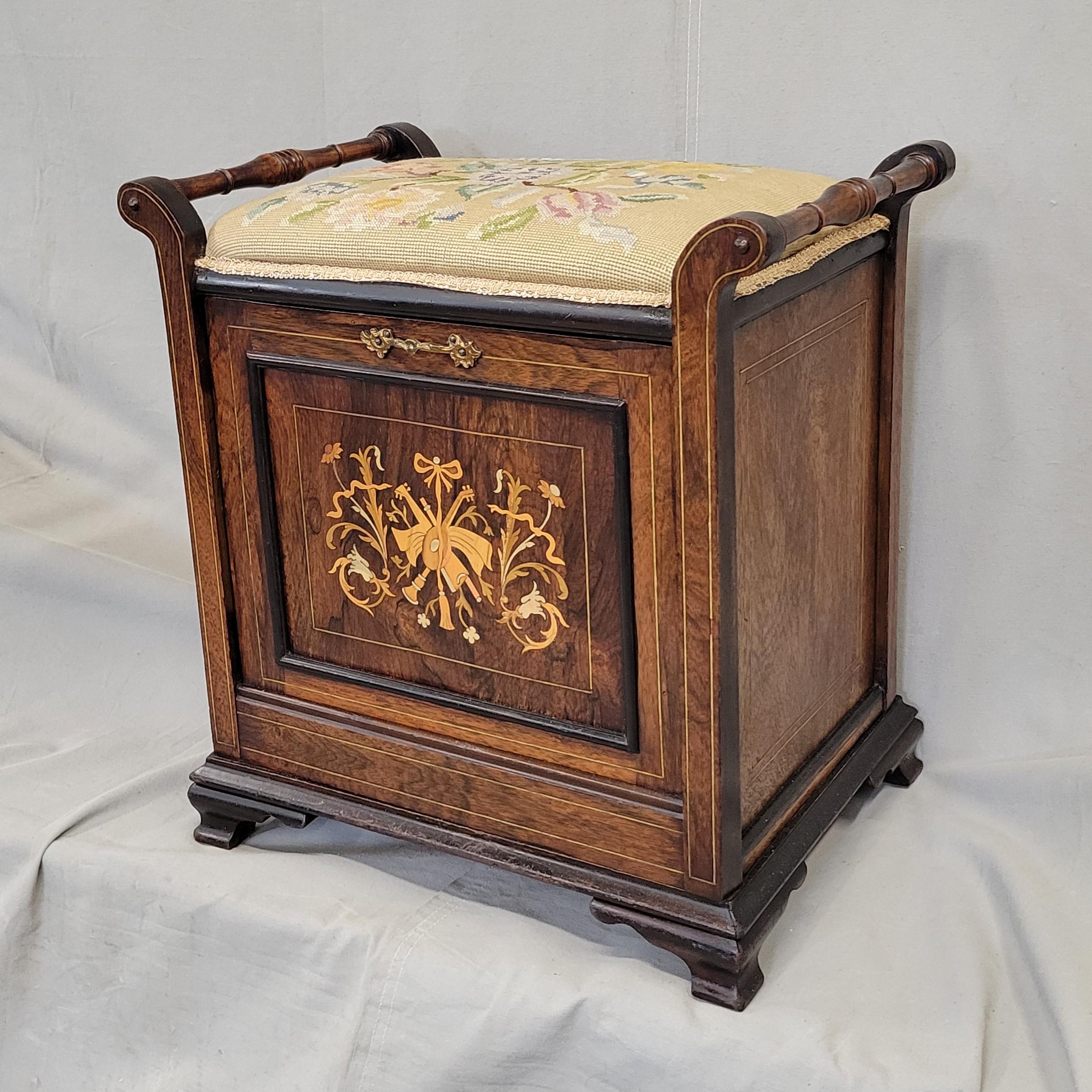 A sweet antique English Edwardian piano stool with tilt out music storage and a needlepoint cushion. The musical instrument inlay on the door is beautiful and in good condition. The door tilts out easily for access to sheet music storage. This stool