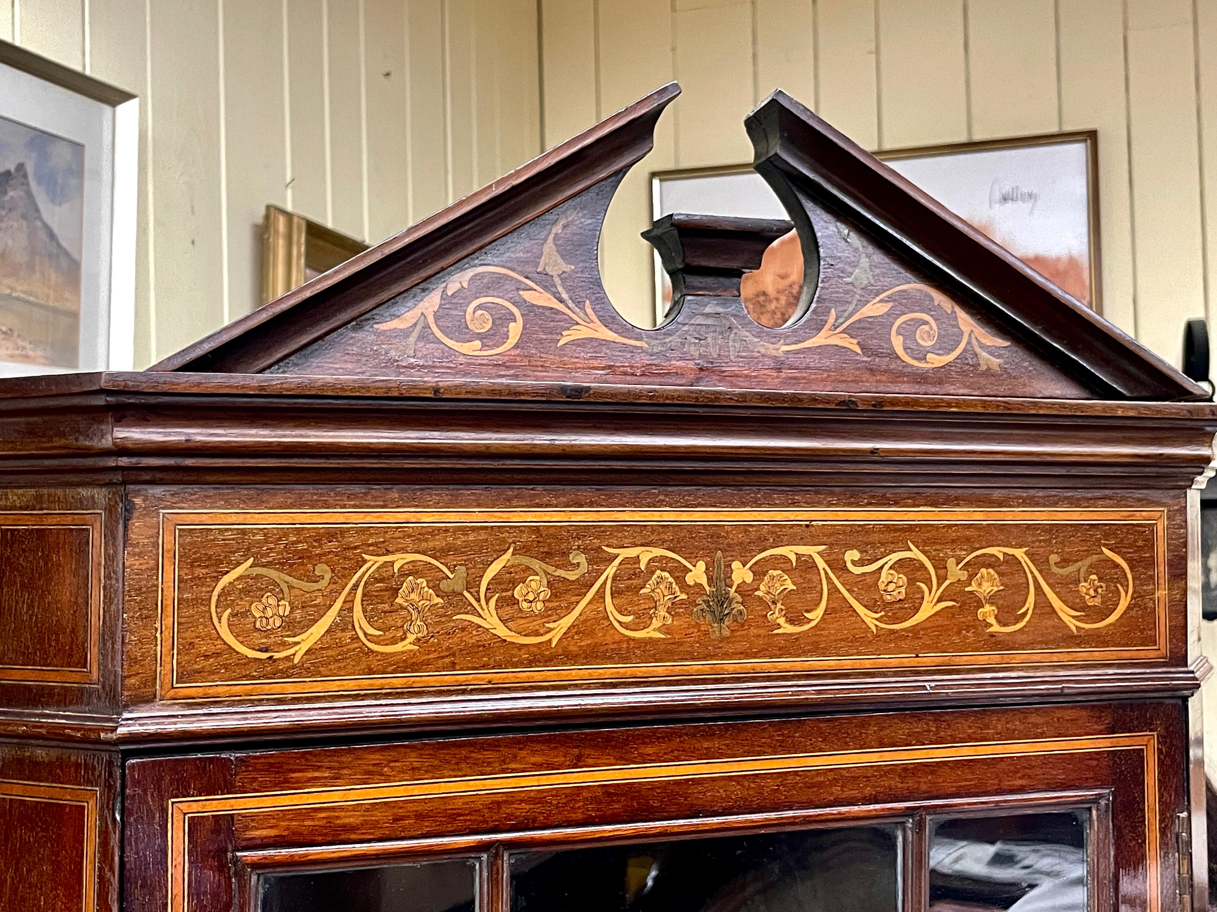 Magnifique armoire d'angle en acajou marqueté de taille réduite, de style anglais édouardien, avec de superbes marqueteries néoclassiques sur l'ensemble de la surface.  Il possède également des portes à double vitrage inhabituelles en haut et en bas.