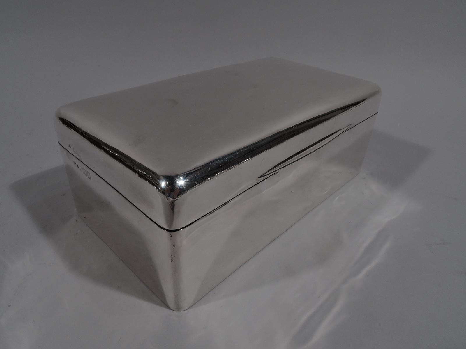 Edwardian modern sterling silver box. Made by Frederick Haberling in London in 1905. Rectangular with straight sides and curved corners. Cover hinged and gently curved with tapering tab. Box and cover interior cedar lined and partitioned. Underside