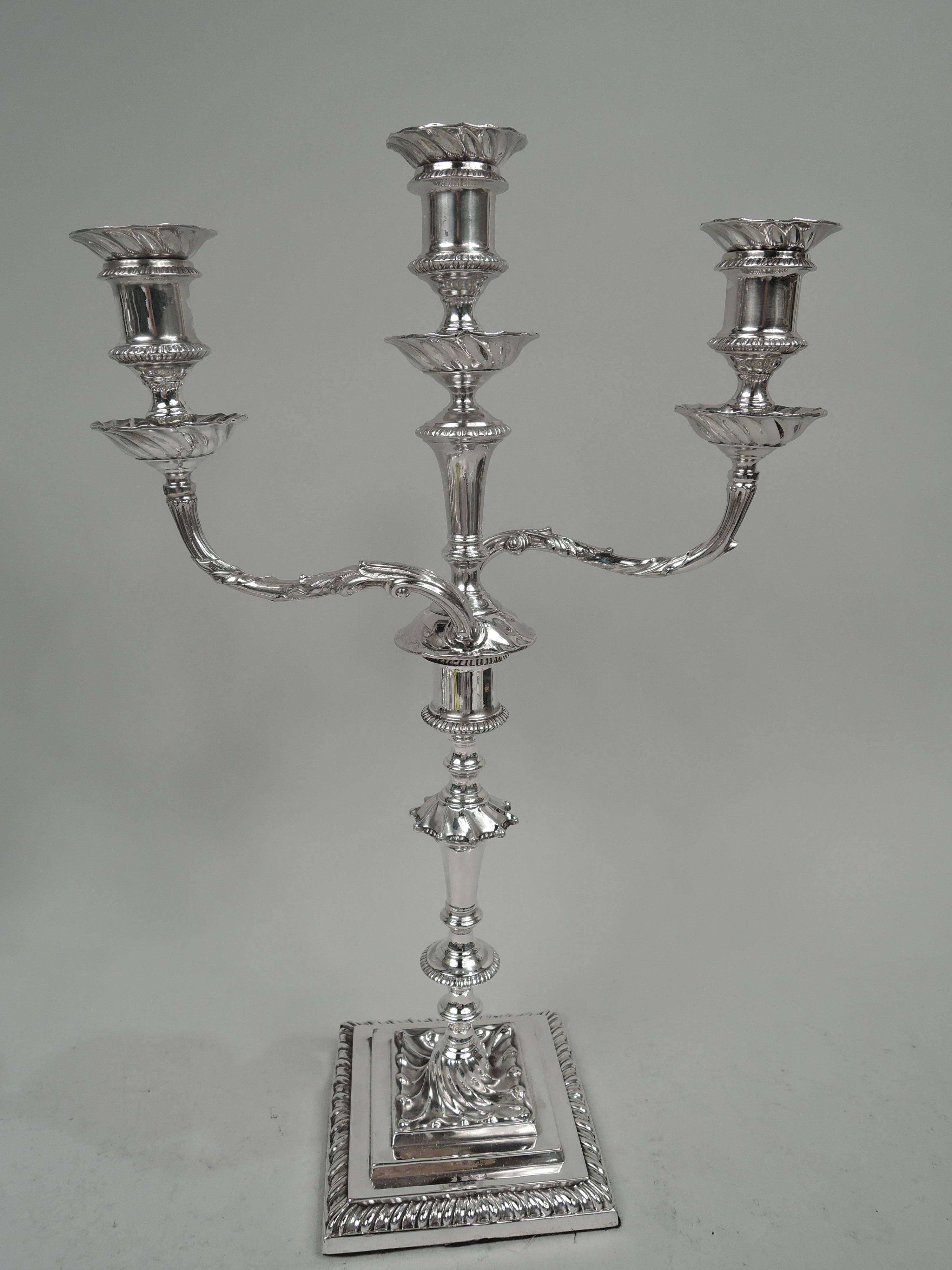 Pair of George V sterling silver 3-light candelabra. Made by Hawksworth, Eyre & Co., Ltd in Sheffield in 1919-1921. Each: Two leaf-wrapped arms, each terminating in single socket wrapped around raised central socket. Sockets spool form with wax pans