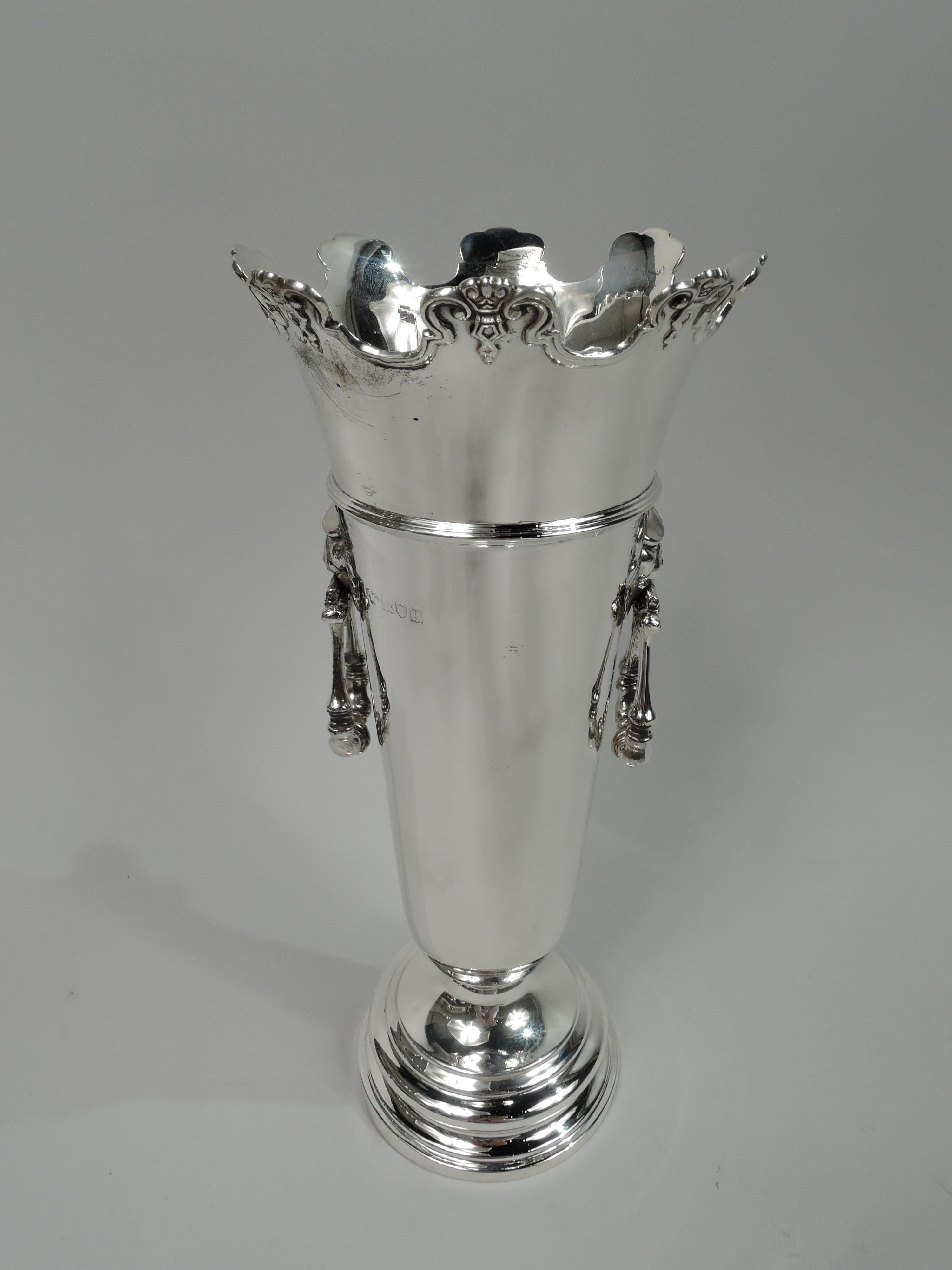 George V sterling silver vase. Made by Goldsmiths & Silversmiths Co. Ltd in London in 1912. Tapering and girdled tube on stepped foot. Flared and castellated rim with applied molding and ornament. Lion’s head side mounts with hinged and turned