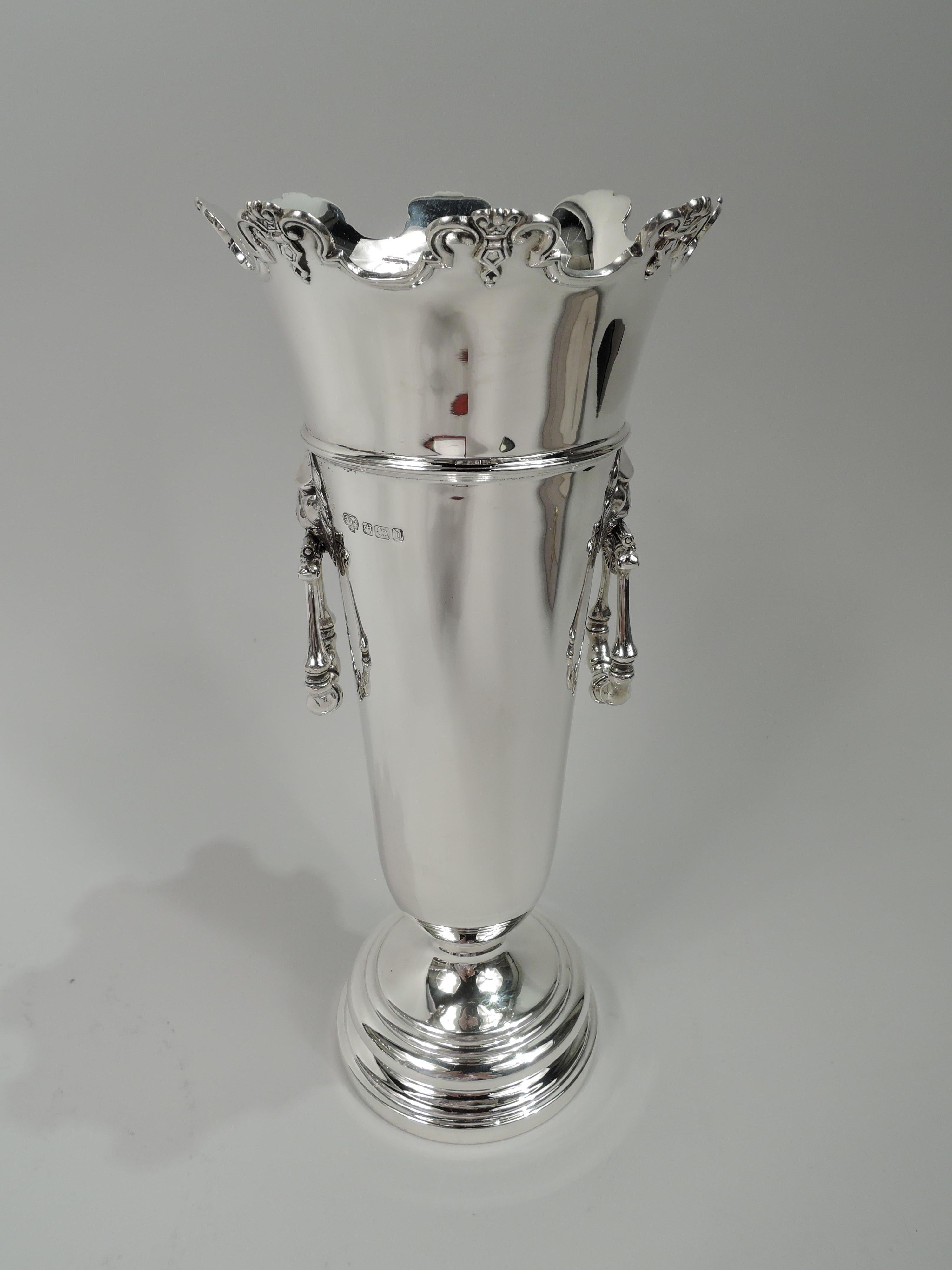 George V sterling silver vase. Made by Goldsmiths & Silversmiths Co. Ltd in Sheffield in 1913. Tapering and girdled tube on stepped foot. Flared and castellated rim with applied molding and ornament. Lion’s head side mounts with hinged and turned