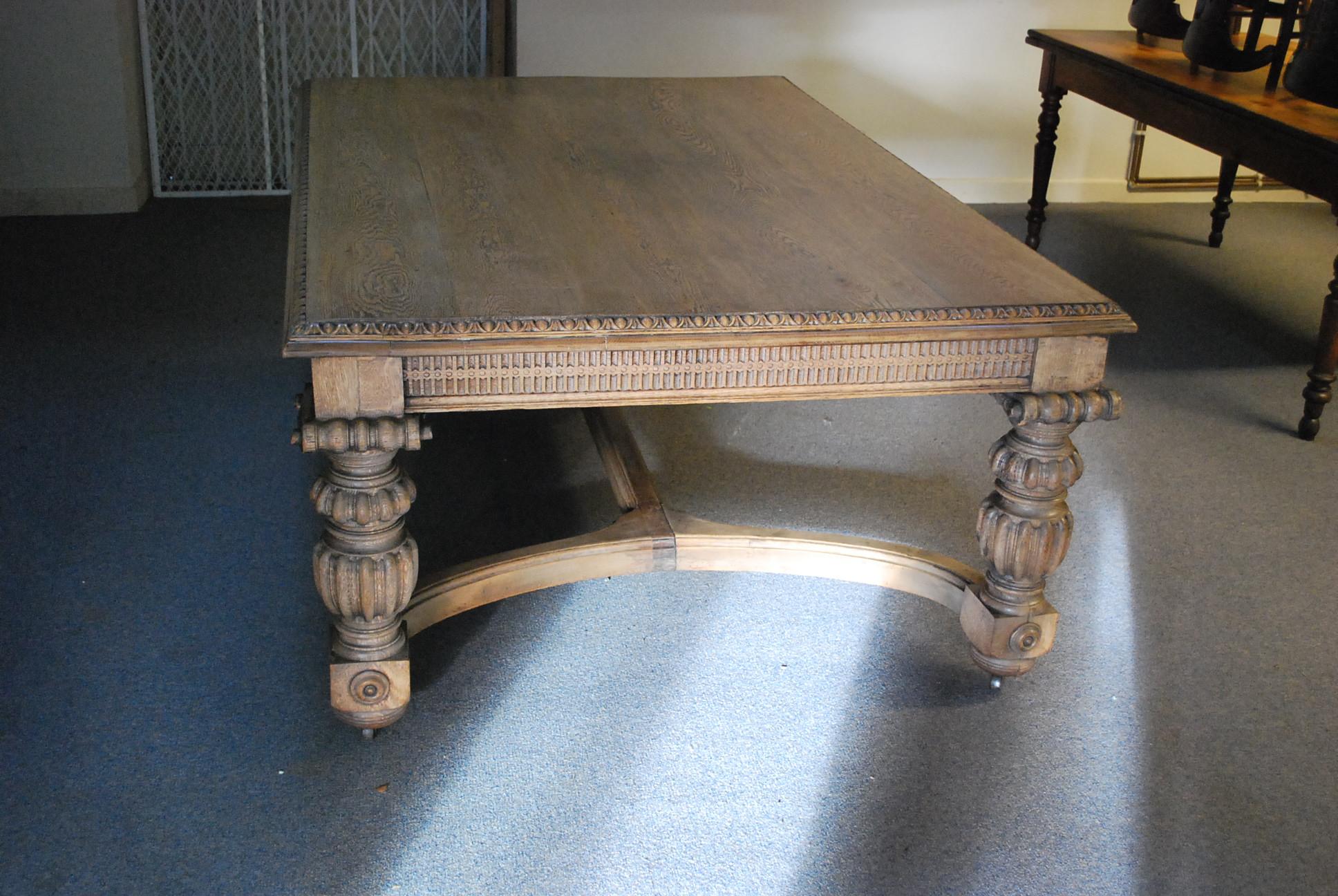 Antique English Edwardian period oak dining table, in the Elizabethan style. Standing on carved column legs united by shaped stretchers, allowing plenty of legroom all around. The top is a good width in solid oak with a egg and dart border. Below