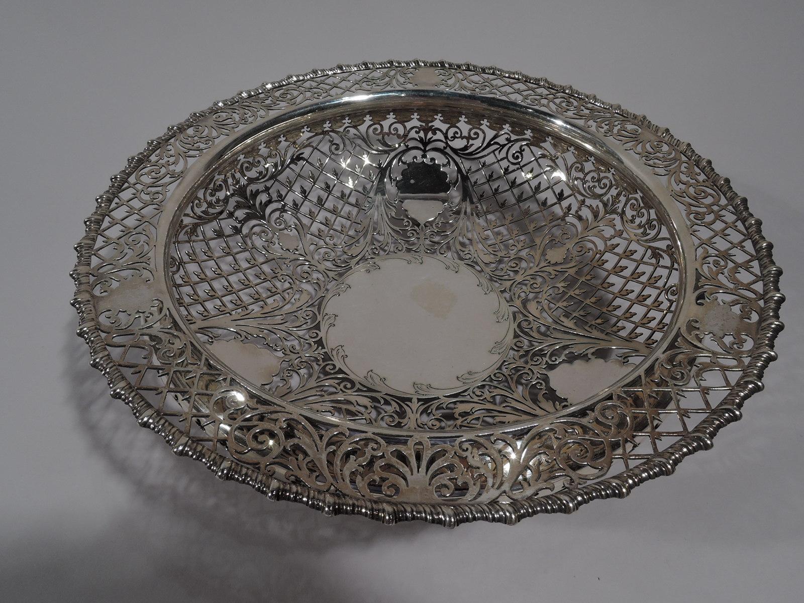 Edwardian sterling silver bowl. Made by James Dixon & Sons in Sheffield in 1904. Bellied with flat shoulder and gadrooned rim. Solid circular well (vacant) surrounded by 3 multifoil frames (vacant) set between leafy scrolls. All-over open diaper