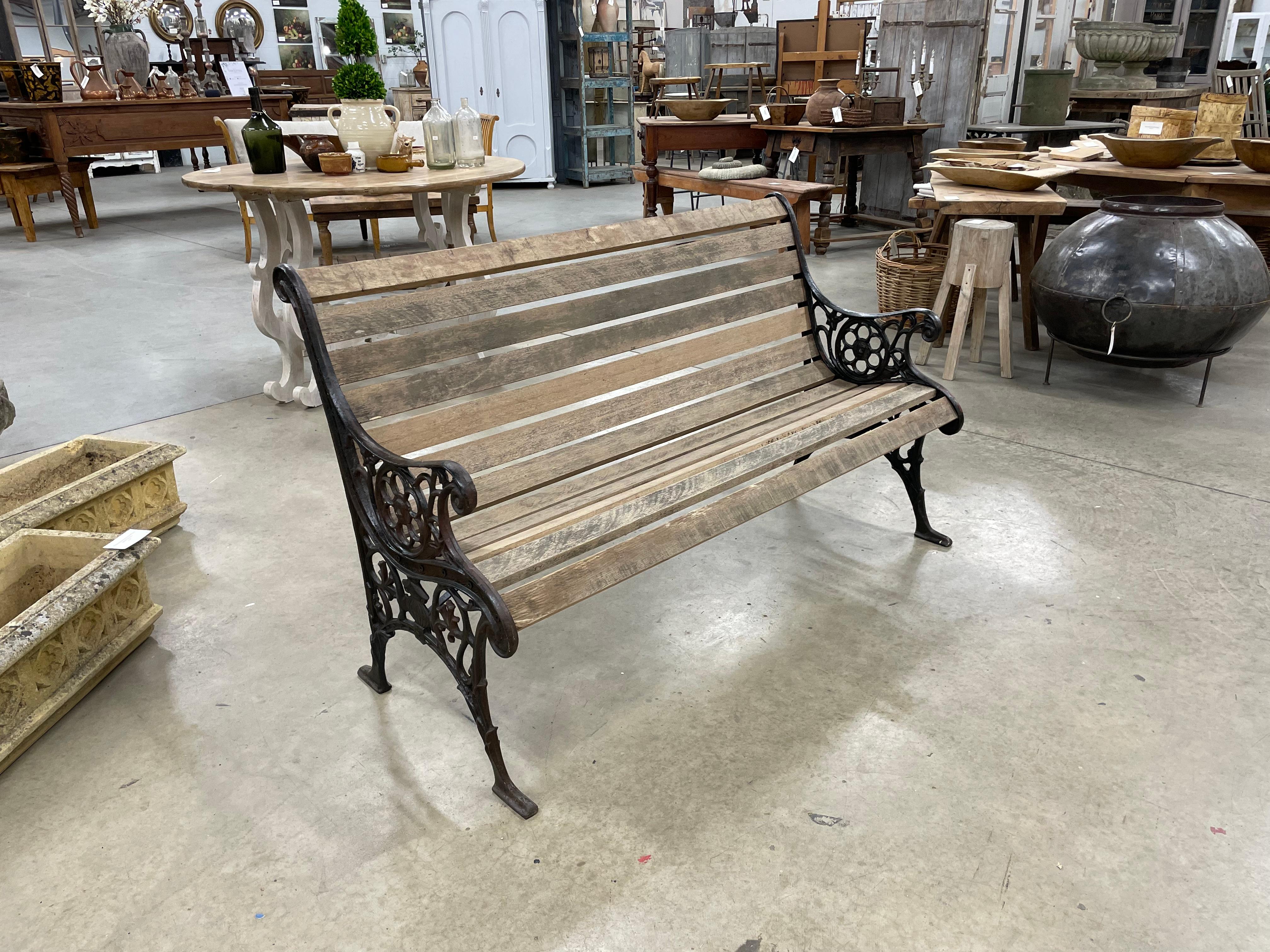 Antique English Edwardian wooden slatted curved back bench with decorative cast iron sides and lion head medallions.