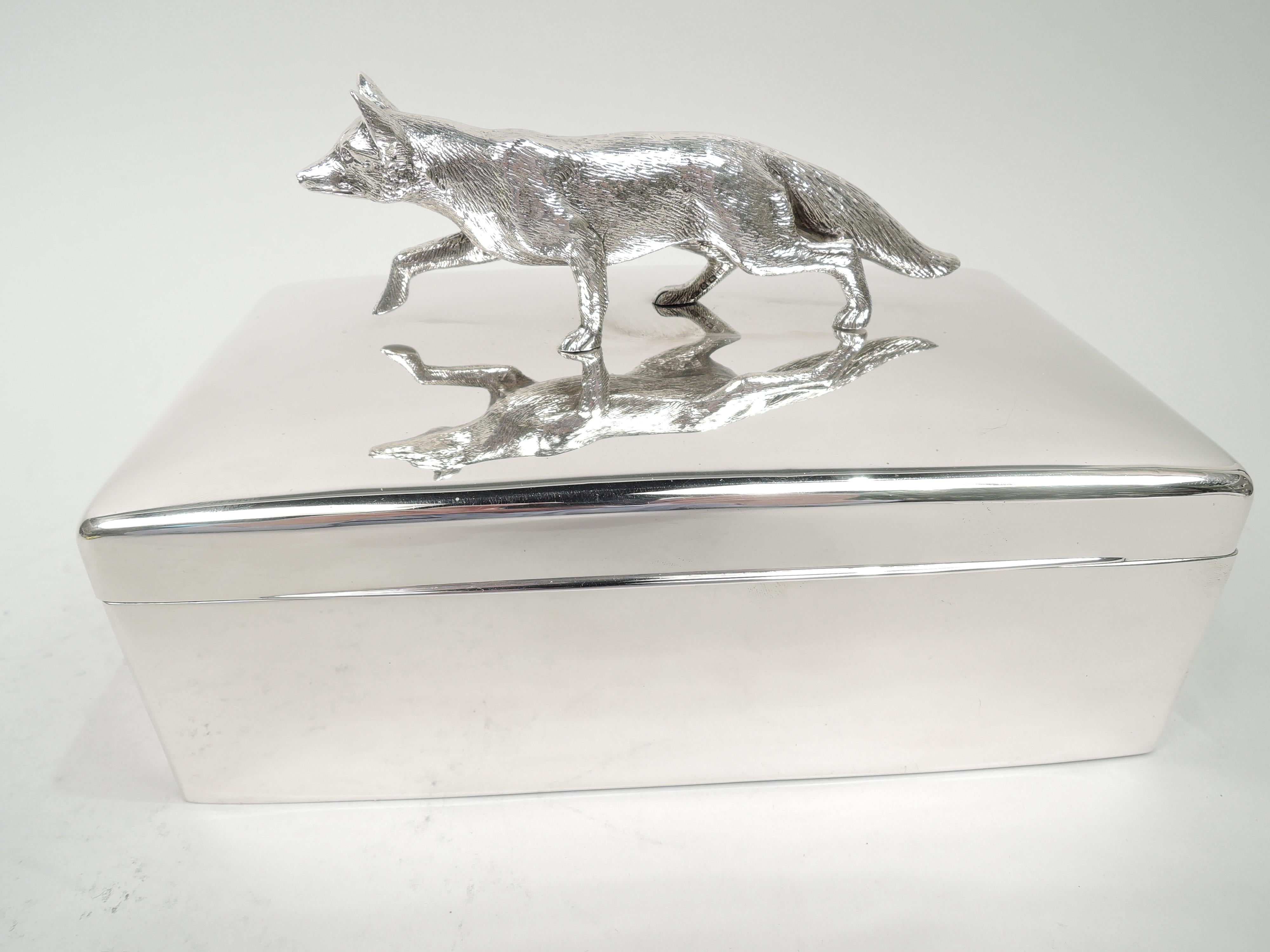 Edwardian sterling silver box. Made by George R. Unite in Birmingham in 1906. Rectangular with straight sides and curved corners. Cover hinged with flat top and tapering tab. Cast finial in form of loping fox with direct stare and alert ears.