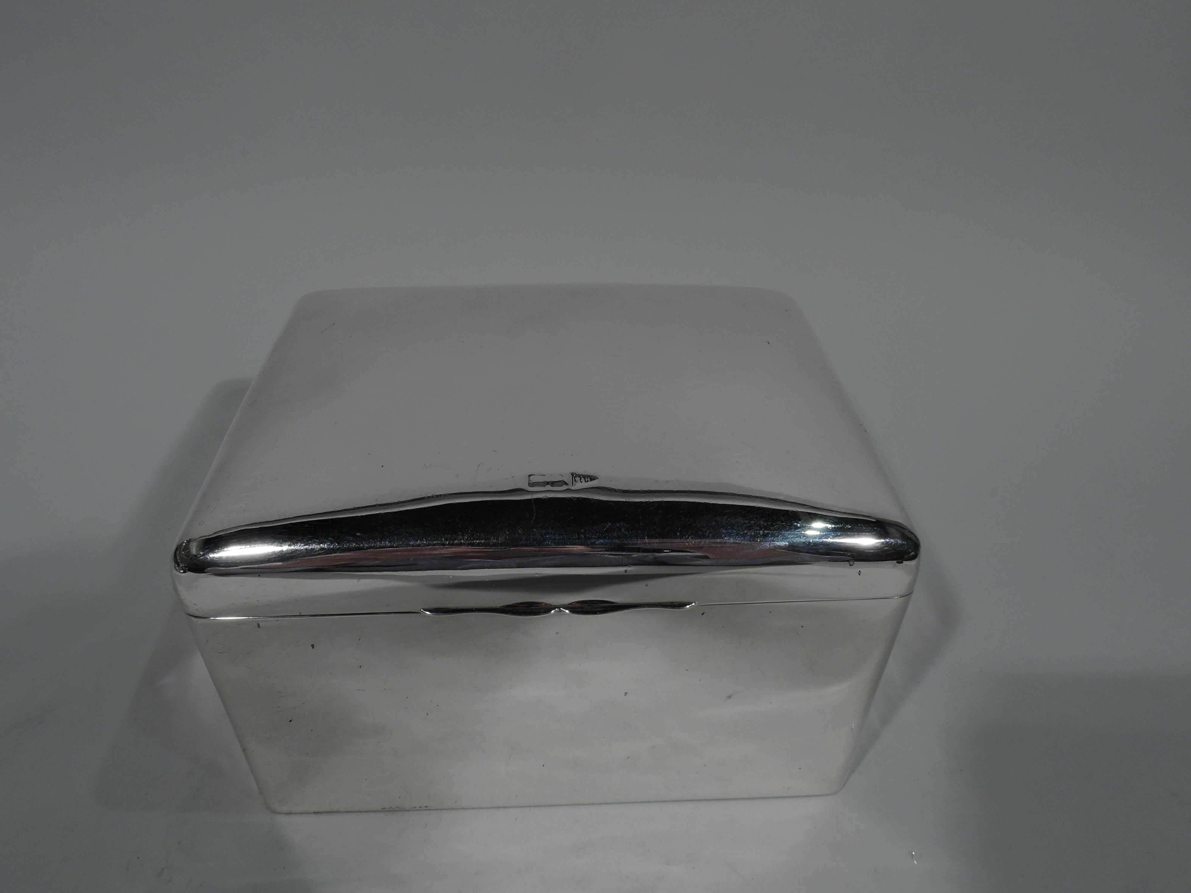 Edwardian sterling silver box. Made by Walker & Hall in Chester in 1906. Rectangular with straight sides and curved corners. Cover curved and hinged with double-scroll tabs. Box interior wood-lined. Cover interior gilt. Box underside leather-lined.