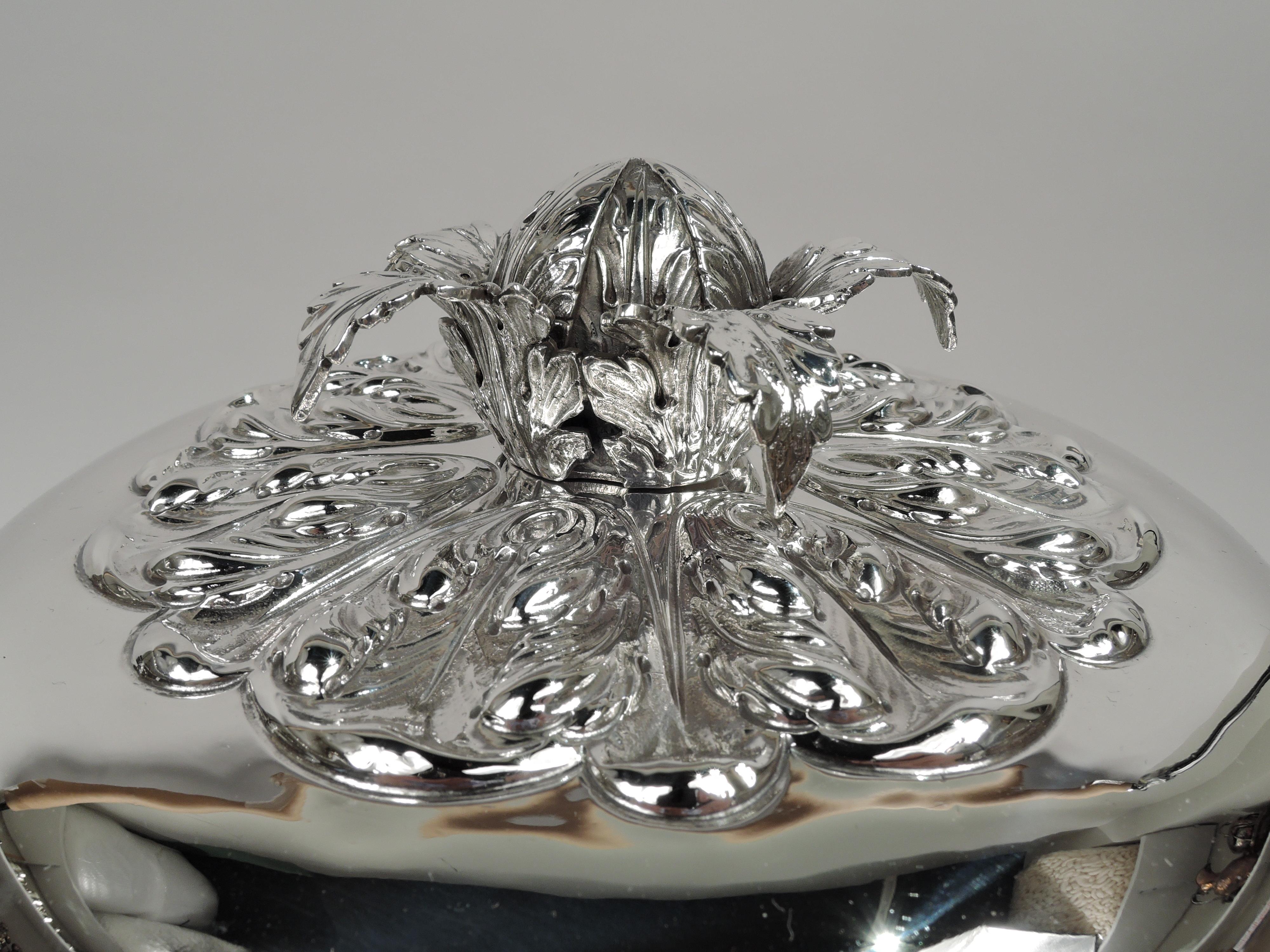 Urna eduardiana cubierta de plata de ley. Fabricado por William Comyns en Londres en 1908. El cuenco tiene los lados rectos y el fondo curvado, con asas laterales en forma de s con tapa de hoja y envueltas, y pie escalonado encastrado. Franja de