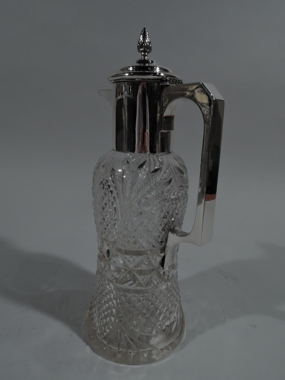 Edwardian cut-glass and sterling silver decanter. Made in Birmingham in 1910. Waisted cylinder with all-over ferns, facets, and stars. Sterling silver bracket handle, neck collar, and stepped and hinged cover with bud finial and spout. Fully marked