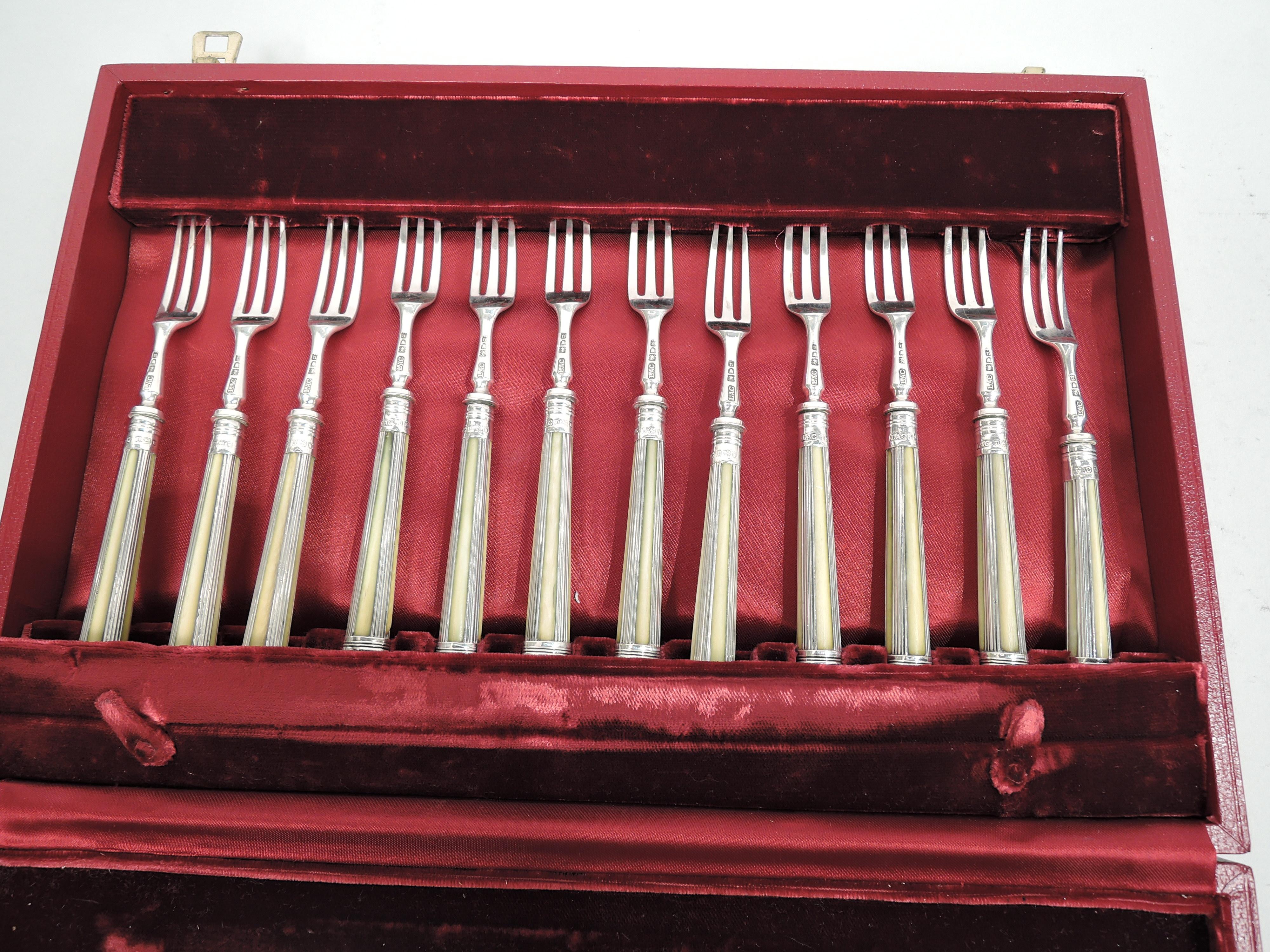 George V sterling silver fruit set. Made by Lionel Alfred Crichton in London in 1915. This set comprises 24 pieces: 12 forks and 12 knives. Each: Tapering handle with reeding and volute scroll terminal. In leather-bound case with fitted velvet.