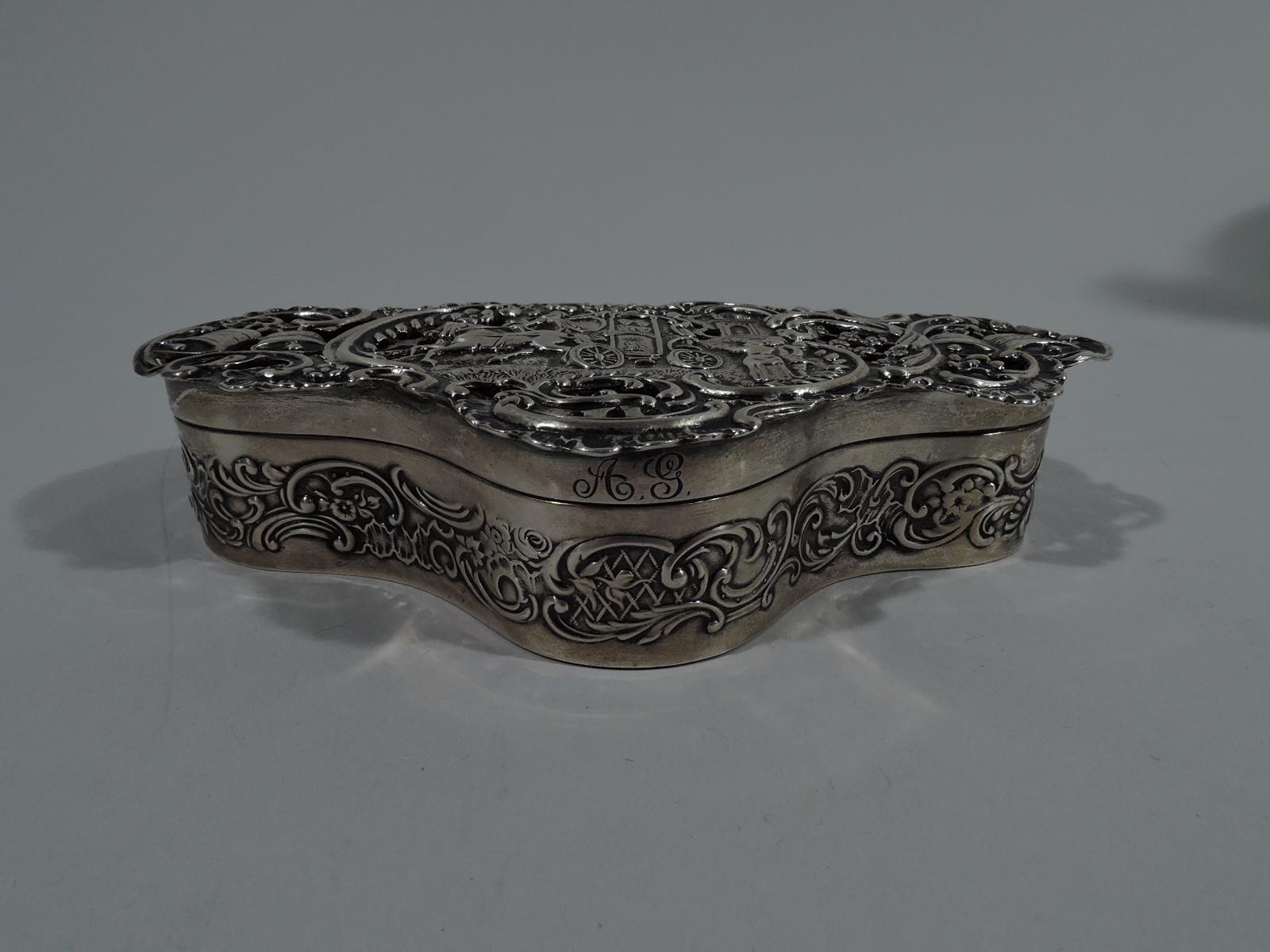 Edwardian sterling silver box with Georgian coaching days scene. Made by William Comyns in London in 1905. Shaped trefoil with chased and pierced ornament. Sides have scroll-and-flower band. Overhanging cover with royal coach waved on by loyal