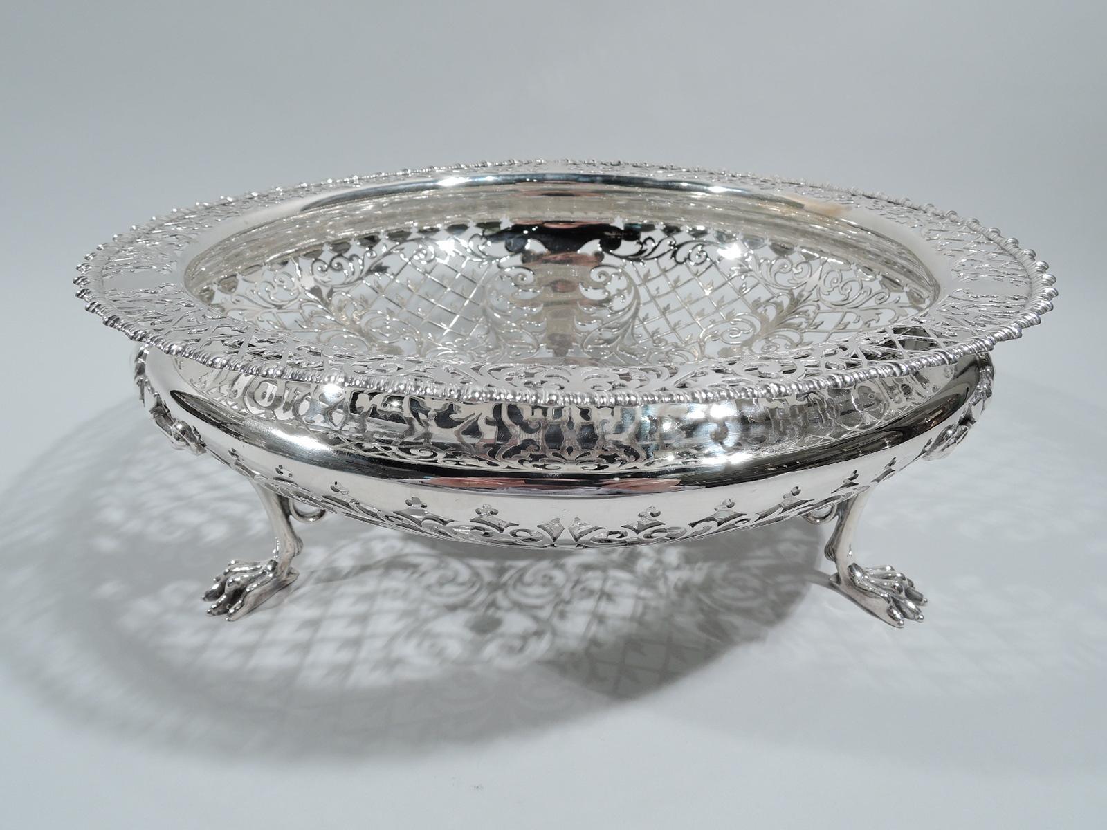 Edwardian sterling silver bowl. Made by Goldsmiths & Silversmiths Co. Ltd in London in 1905. Bellied with flat shoulder and gadrooned rim. Three leaf and scroll-mounted talon supports. Well circular and solid (vacant). Solid leafy ornament in open