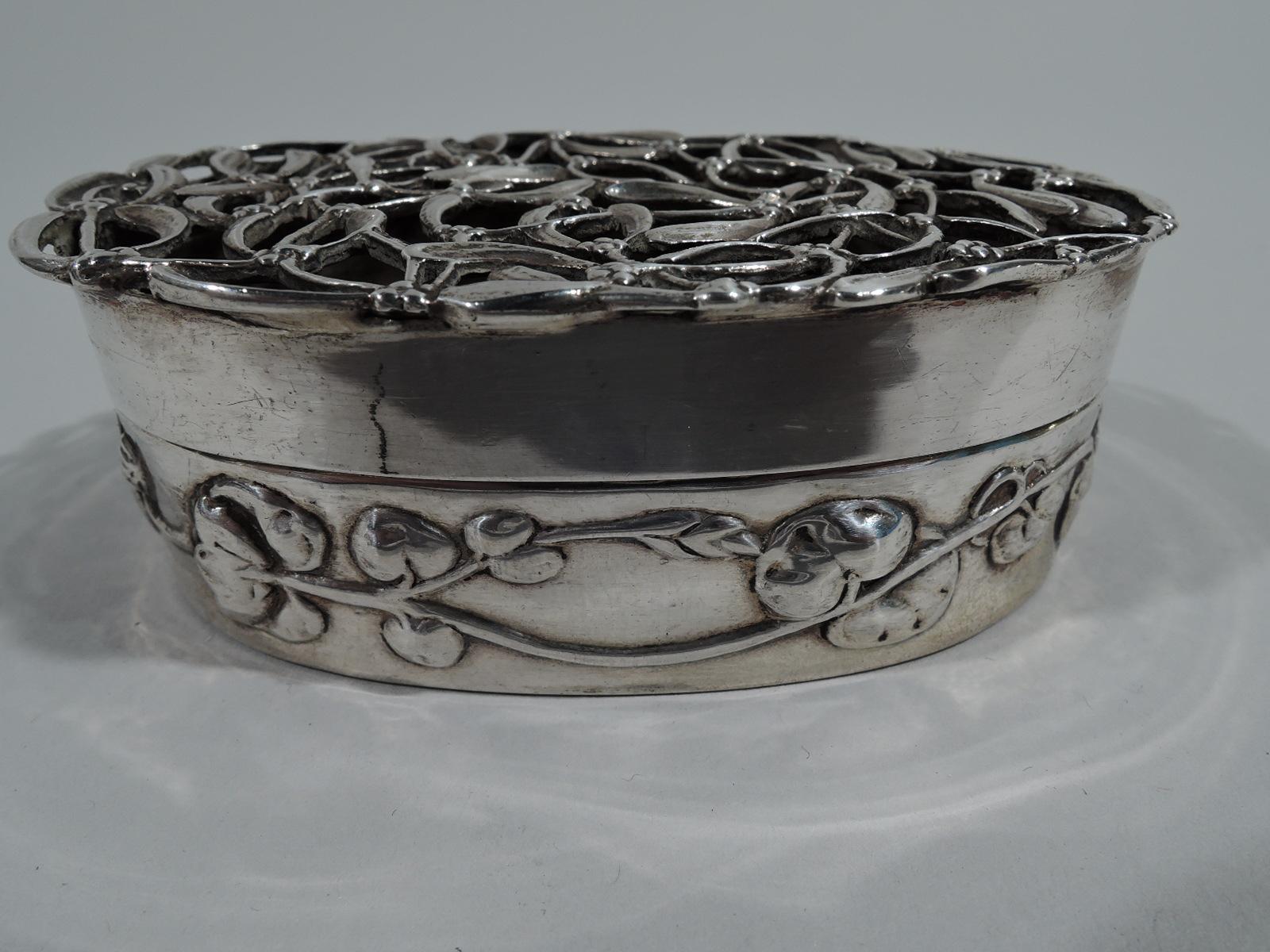 Edwardian sterling silver trinket box. Made by William Comyns in London 1909. Oval with straight sides and chased flowering and leafing tendril. Open cover top comprising leaves and berries. Fully marked. Numbered A1330. Weight: 1.5 troy ounces.