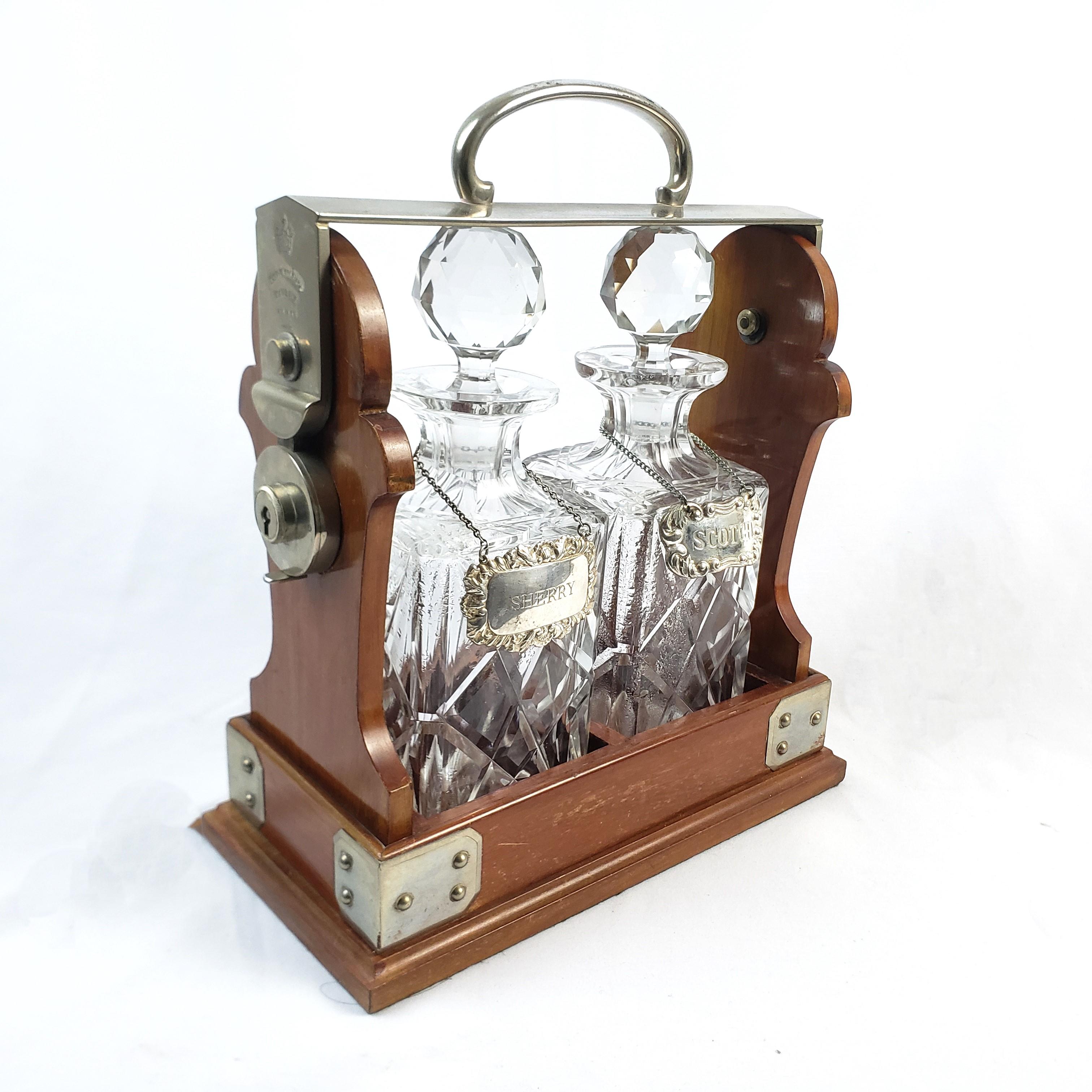 This antique tantalus set was made by the well known Betjemmin's & Sons of London, England and dates to approximately 1900 and done in the period Edwardian style. The carriage is composed of wood with silver plated corner accents and tilt mechanism.