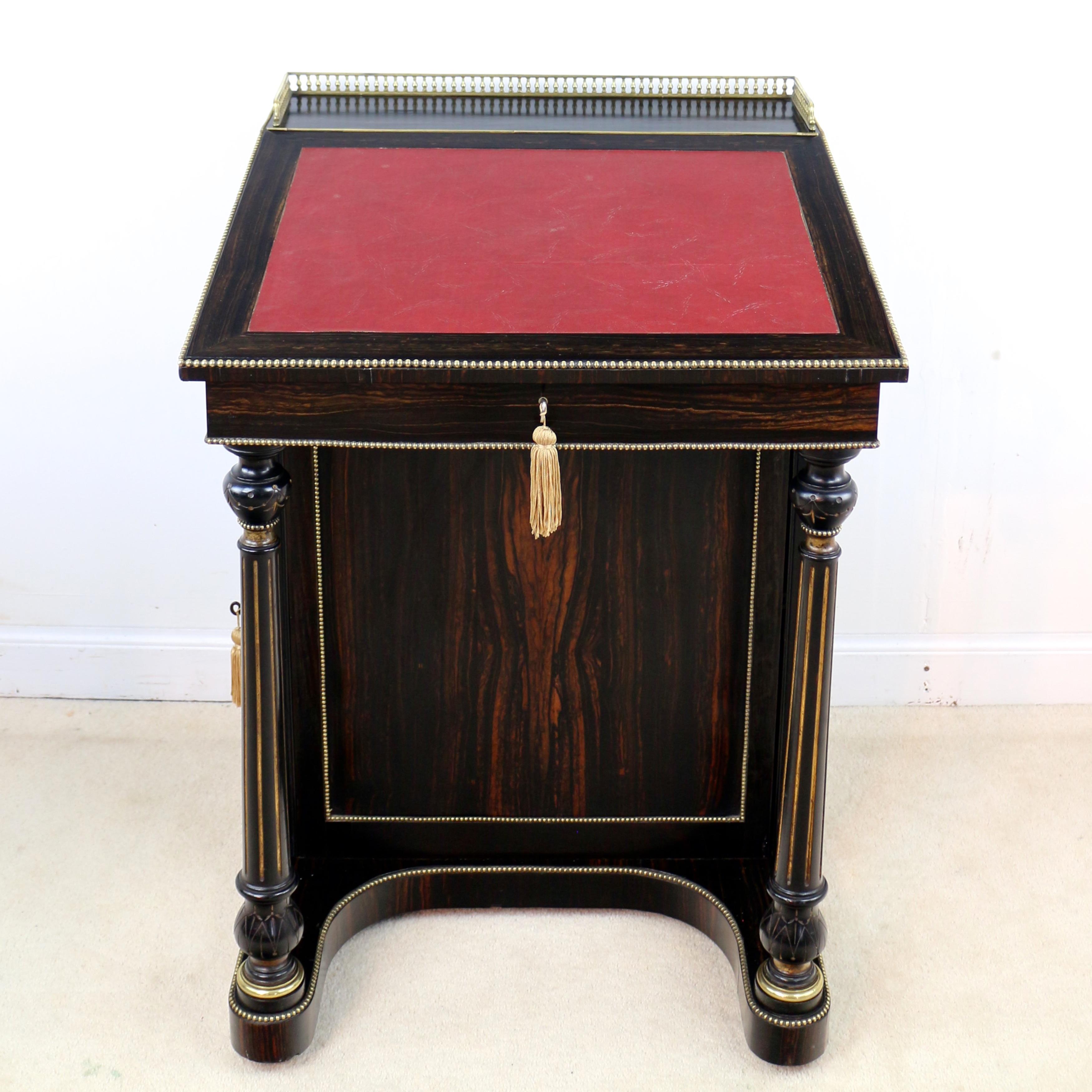 A rare 19th century Coromandel davenport by Edwards & Roberts of London. Featuring beautiful dark Coromandel veneers to each side highlighted with brass beading and turned and fluted gilt decorated ebonized columns. The top with a brass gallery and