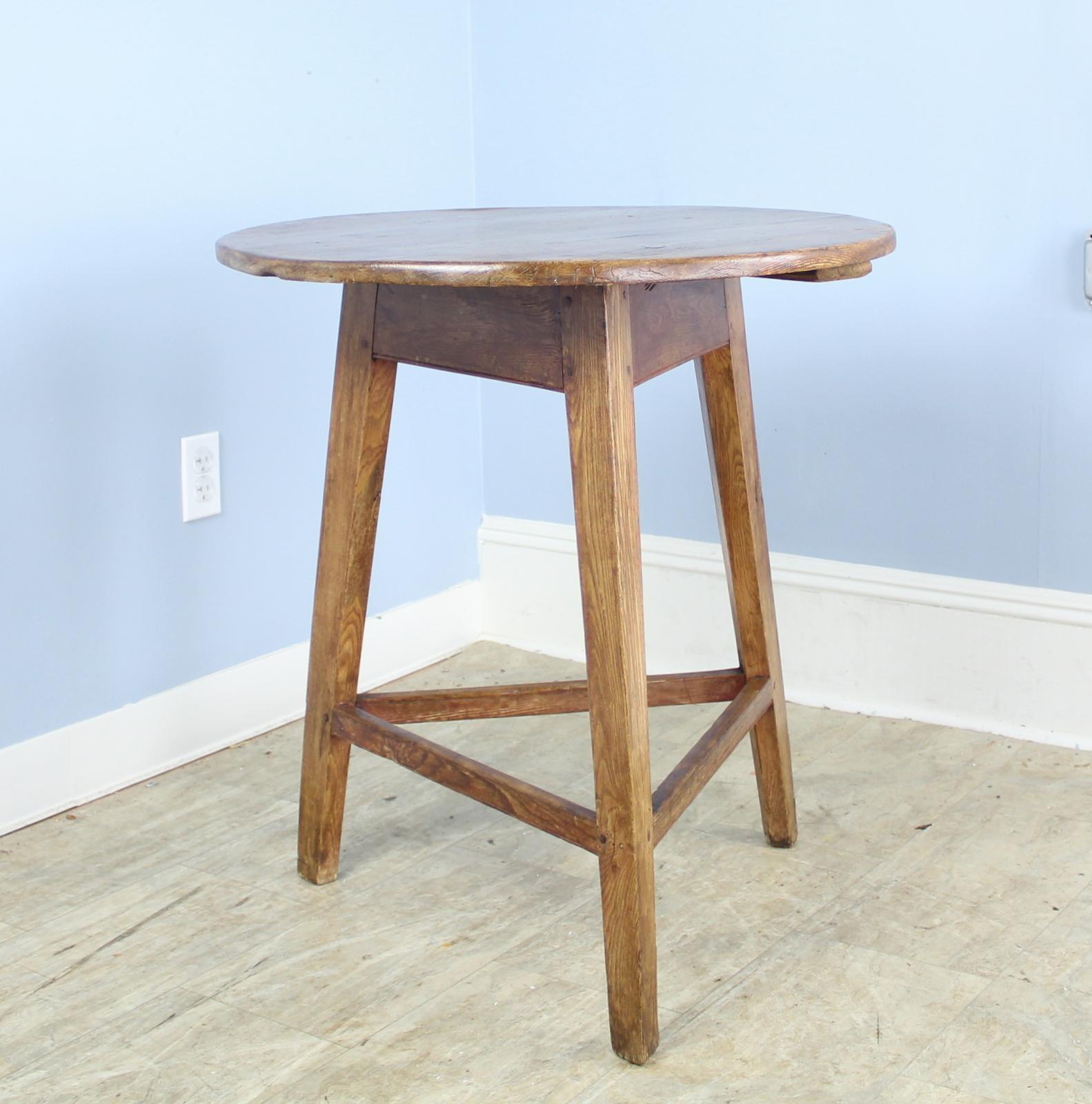 A pretty cricket table with suitable height for use as a good side, lamp or occasional table. The pine top has rich color and good patina. Traditional tripod base construction with a rustic elm base and lower stretchers. The piece is quite early,