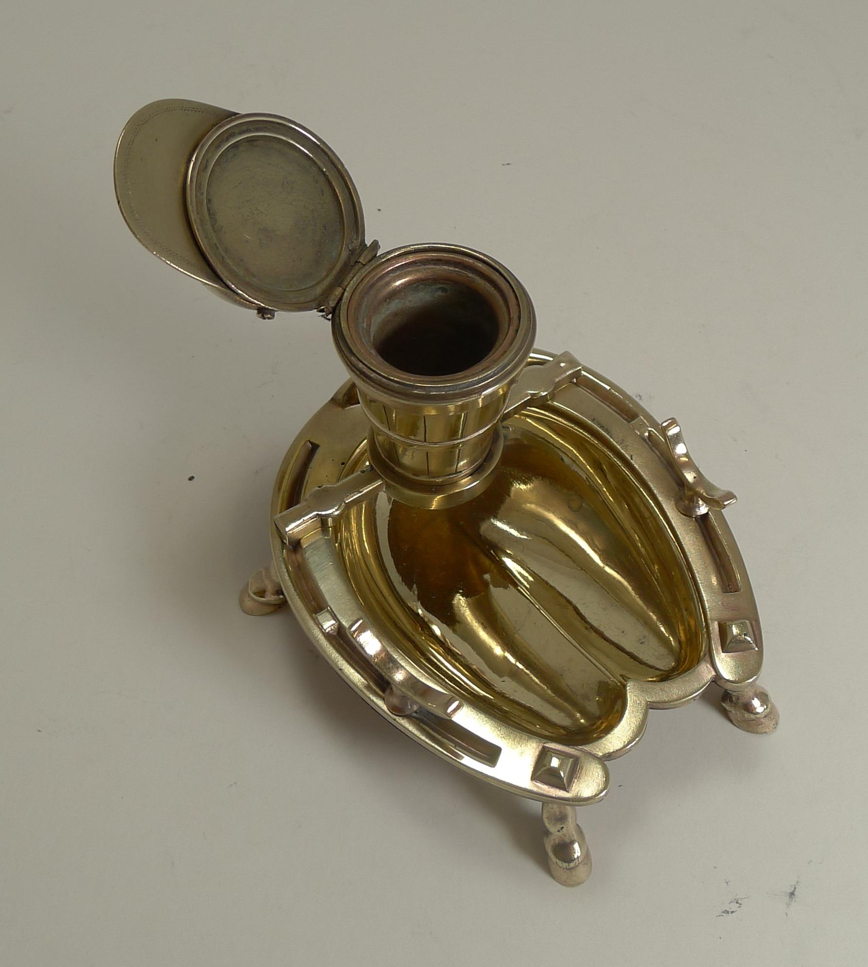 A handsome heavy cast brass inkwell with a highly collectable Equestrian theme. The horseshoe shaped base stands on four horse hoof legs, the tray having a cradle each side acting as a pen rest.

The inkwell itself is in the from of a coopered