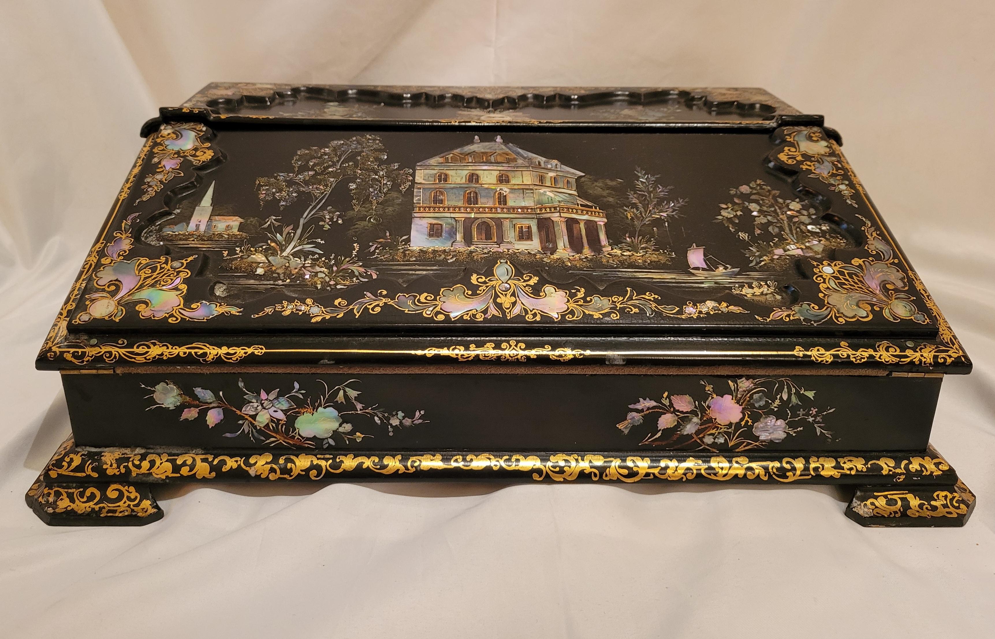This writing slope (or portable writing desk) is richly decorated with mother-of-pearl and pleasing painted florals. It is a little jewel in and of itself. The laquer is very nice, with a high gloss.
