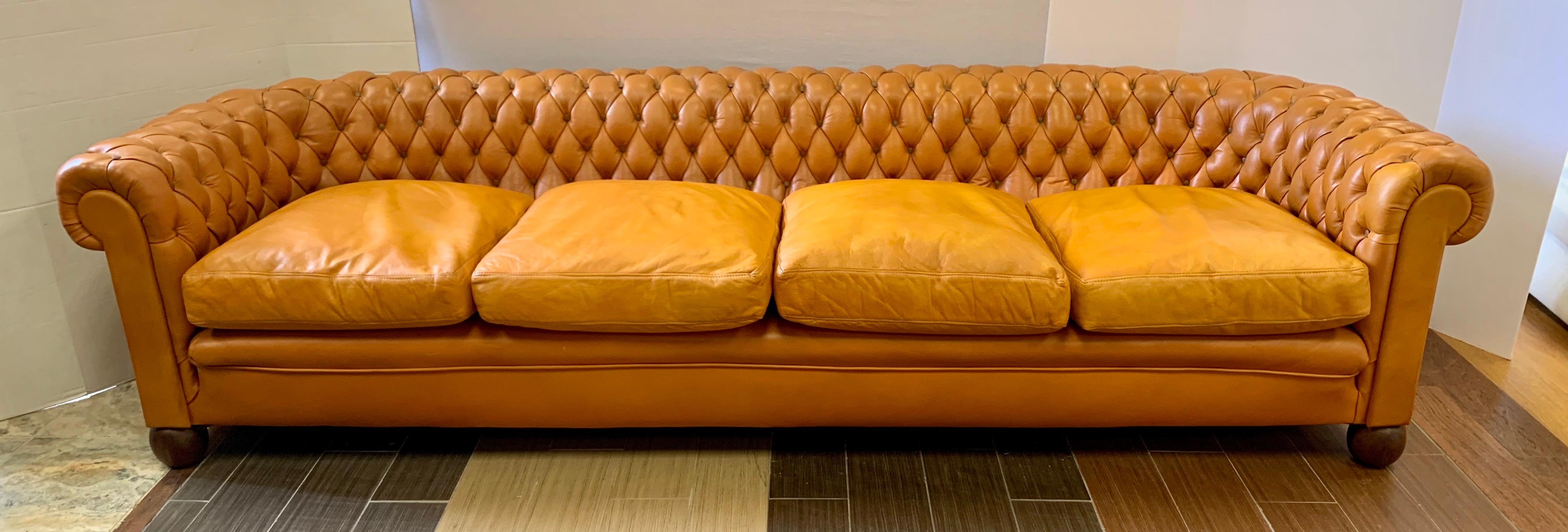 Antique extra large chesterfield sofa features distinctive, rolled arms and deep buttoned tufted detailing and is upholstered in the softest top-grain, butterscotch colored leather accented with brown button tufting. Feels as luxurious as it looks.