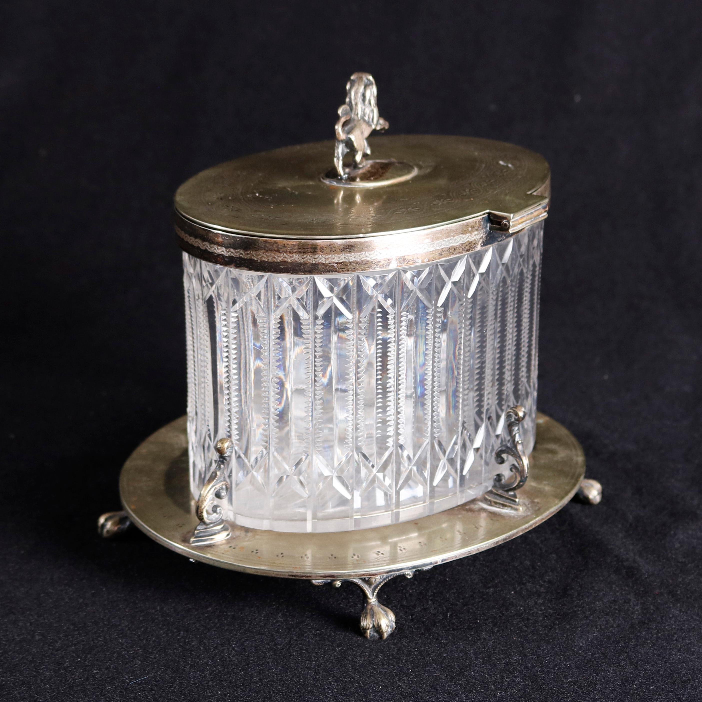 An antique English Regency Mappin and Webb biscuit jar offers cut crystal jar with hinged figural silver plate lid having lion passat finial, seated on decorated silver plate base with scrolled foliate supports and claw and ball feet, circa
